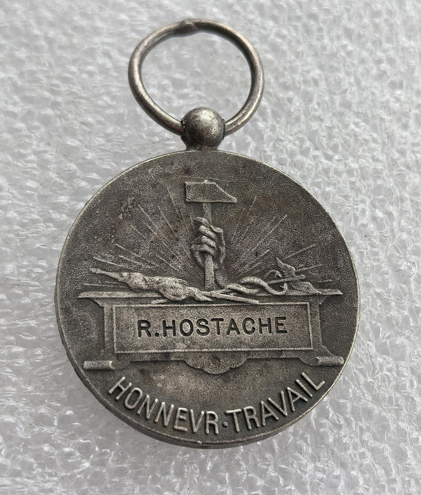 外国优质老铜币高银银币，周六九点倒数截拍，满百包邮，持续收拍 法国荣誉劳动奖章直径26.8mm,10克，正面铸共和女神玛丽安娜，背面刻名 “R.HOSTACHE” 与 “HONNEUR・TRAVAIL”（荣誉与劳动），带原装挂环，品相完好，历史质感浓郁，是法国第三共和国时期劳动荣誉的实物见证，收藏与纪念价值兼具。