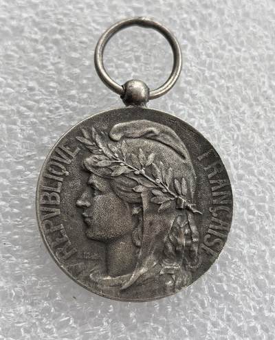 外国优质老铜币高银银币，周六九点倒数截拍，满百包邮，持续收拍 - 法国荣誉劳动奖章直径26.8mm,10克，正面铸共和女神玛丽安娜，背面刻名 “R.HOSTACHE” 与 “HONNEUR・TRAVAIL”（荣誉与劳动），带原装挂环，品相完好，历史质感浓郁，是法国第三共和国时期劳动荣誉的实物见证，收藏与纪念价值兼具。