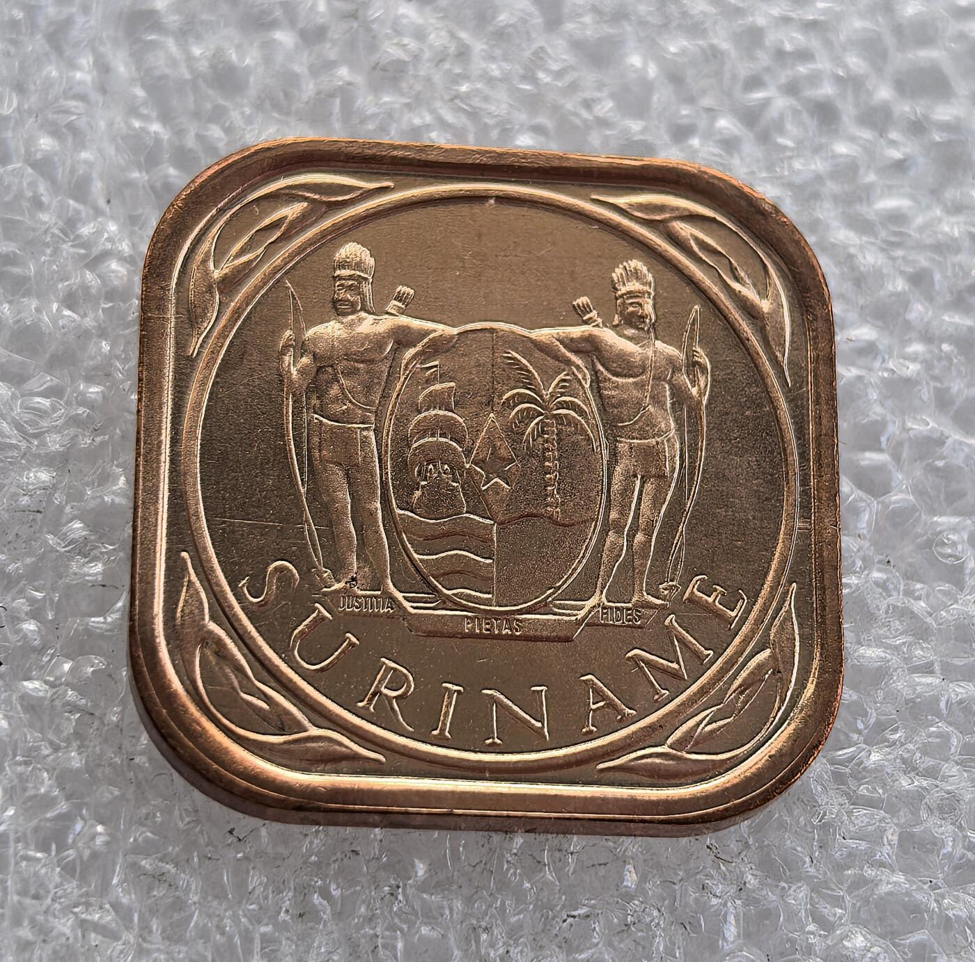 外国优质老铜币高银银币，周六九点倒数截拍，满百包邮，持续收拍 苏里南1988 年 5 分铜币为方形圆角独特形制，正面饰缠枝纹与面值，背面铸苏里南国徽（原住民武士 + 正义 / 虔诚 / 忠诚铭文）。铜质光泽温润，品相完好，属苏里南独立后经典辅币，兼具形制特色与历史收藏价值。