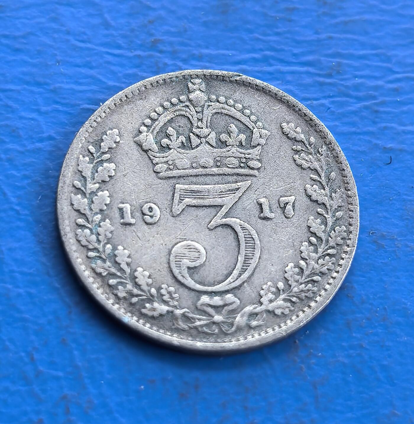 外国优质老铜币高银银币，周六九点倒数截拍，满百包邮，持续收拍 英国1917 年 3 便士银币，正面乔治五世头像雕刻细腻传神，铭文环绕排布规整；背面皇冠衬数字 3，月桂枝对称环绕，年份清晰醒目，纹饰典雅古朴，银质包浆温润，尽显一战时期英伦钱币的精湛工艺与经典美学。