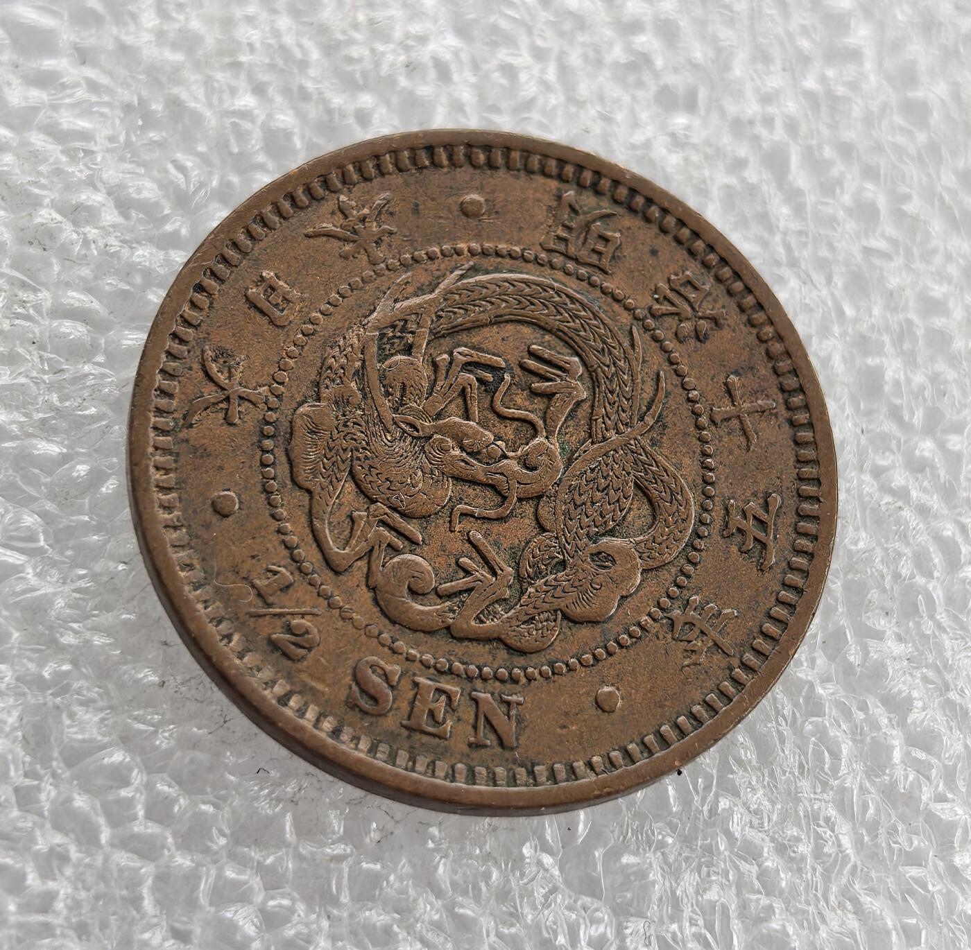 外国优质老铜币高银银币，周六九点倒数截拍，满百包邮，持续收拍 日本明治十五年半钱铜币，正面龙纹刻画精细，搭配国名与面值；背面饰半钱、桐叶菊纹及兑换比例，设计典雅。百年铜质包浆自然醇厚，品相完整，是明治时期龙纹辅币精品，东亚近代货币收藏优选。