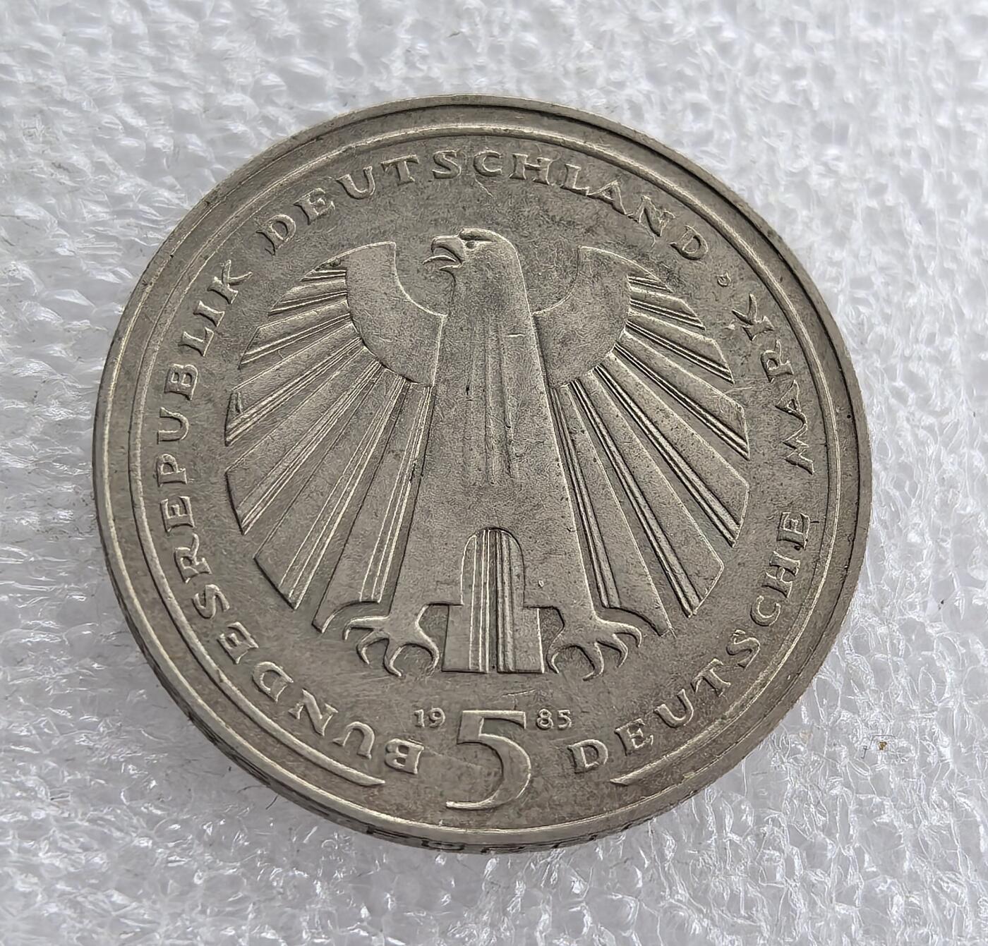 外国优质老铜币高银银币，周六九点倒数截拍，满百包邮，持续收拍 西德1985年5马克纪念币，正面铸联邦德国国徽（联邦之鹰），造型威严经典；背面以车轮图案纪念德国铁路 150 周年，线条流畅、设计精巧，兼具国徽象征意义与工业历史纪念价值，收藏亮点突出。