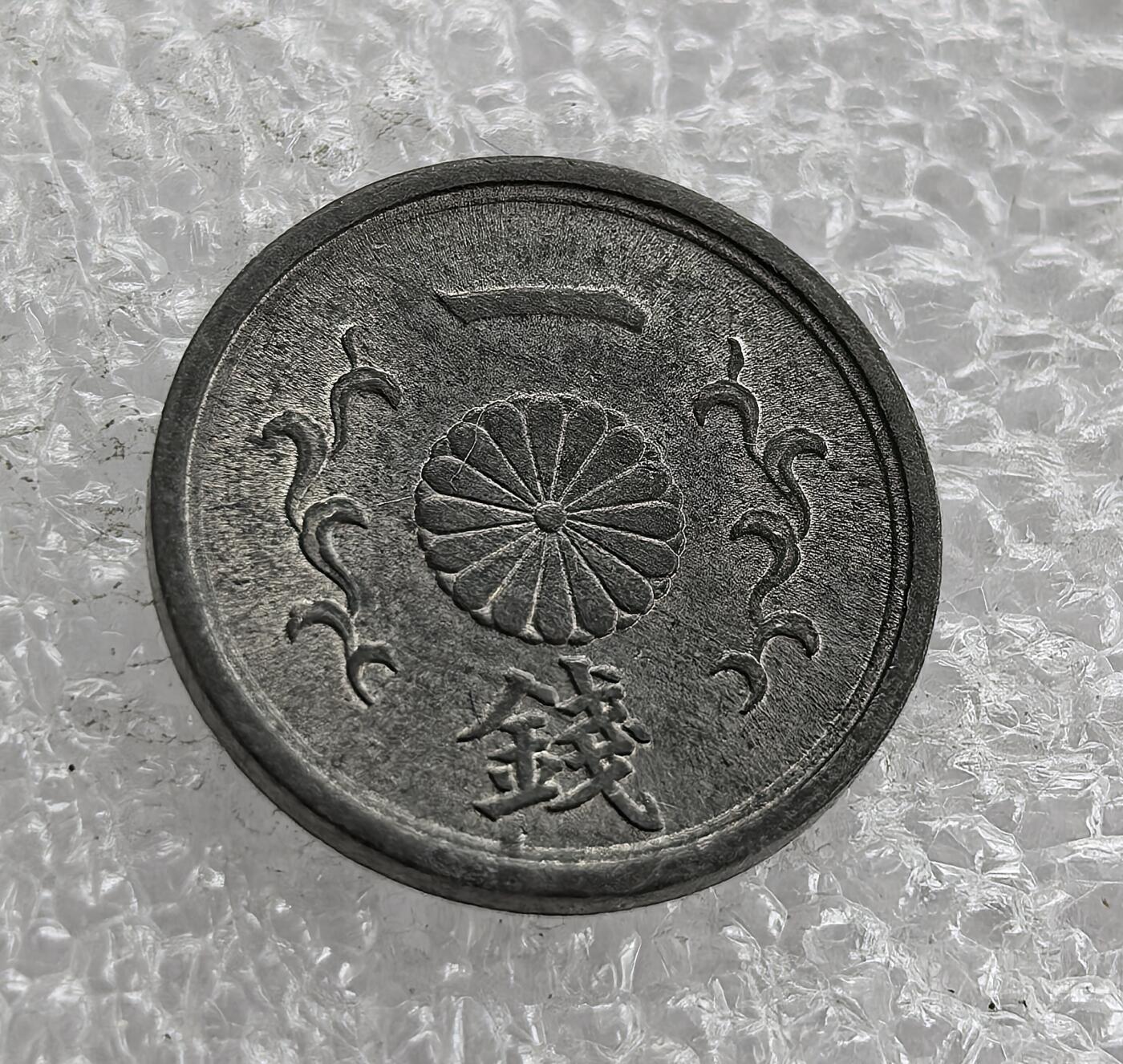 外国优质老铜币高银银币，周六九点倒数截拍，满百包邮，持续收拍 极美品昭和二十年（1945 年）日本一钱锡币，正面皇室菊纹彰显皇权，火焰纹为装饰；背面 “大日本”“昭和二十年” 标注国名与年号。二战末期日本物资匮乏，改用锡铸币，是战时经济崩溃、军国主义走向末路的货币见证