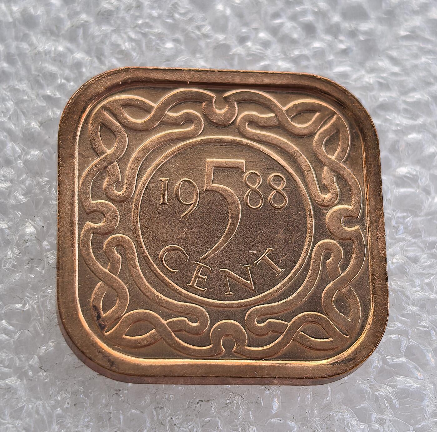 外国优质老铜币高银银币，周六九点倒数截拍，满百包邮，持续收拍 苏里南1988 年 5 分铜币为方形圆角独特形制，正面饰缠枝纹与面值，背面铸苏里南国徽（原住民武士 + 正义 / 虔诚 / 忠诚铭文）。铜质光泽温润，品相完好，属苏里南独立后经典辅币，兼具形制特色与历史收藏价值。