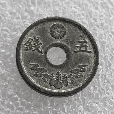 外国优质老铜币高银银币，周六九点倒数截拍，满百包邮，持续收拍 - 极美品昭和十九年（1944 年）日本五钱锡币，正面皇室菊纹彰显皇权，桐叶祥云纹为传统装饰，圆孔形制节省材料；背面 “大日本”“昭和十九年” 标注国名与年号。二战末期日本金属资源匮乏，改用锡铸币，是战时经济崩溃、军国主义走向末路的货币见证