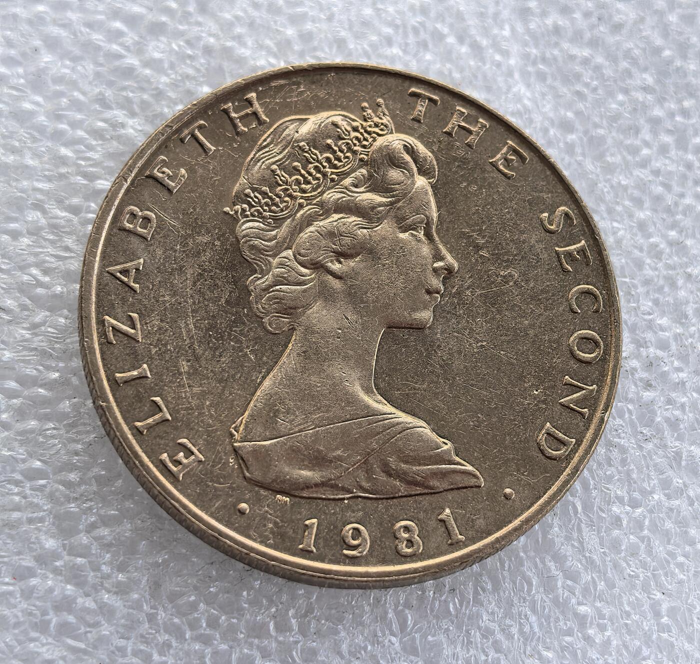 外国优质老铜币高银银币，周六九点倒数截拍，满百包邮，持续收拍 英属马恩岛1981 年 5 镑纪念币，正面铸伊丽莎白二世头像，背面为马恩岛标志性三曲腿图（三腿人），搭配属地标识，属英联邦海外领地经典纪念币，三曲腿图是马恩岛核心文化象征，彰显其独特自治地位。