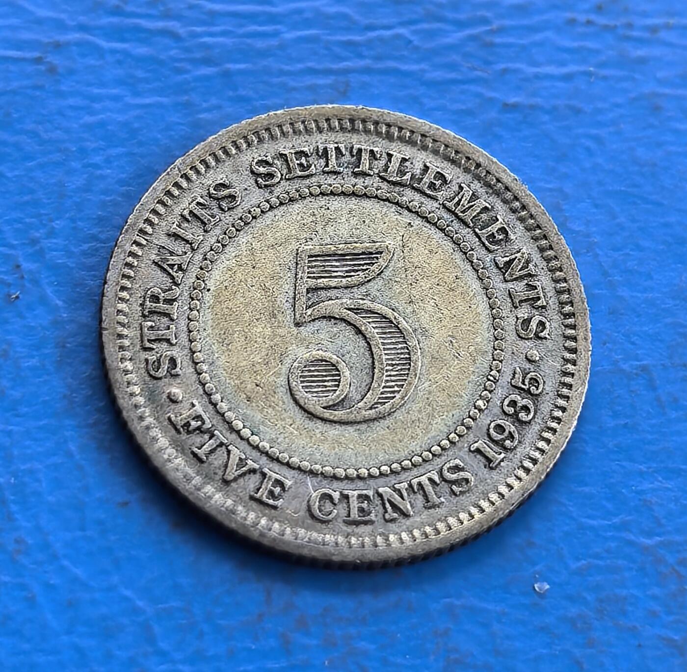 外国优质老铜币高银银币，周六九点倒数截拍，满百包邮，持续收拍 海峡殖民地1935 年 5 分银币，正面乔治五世头像雕刻传神，“英属印度皇帝” 铭文环绕规整；背面海峡殖民地标识、5 分面值与年份清晰排布，数字 5 设计醒目，纹饰简洁对称，殖民风格浓郁，金属质感古朴，工艺精致。