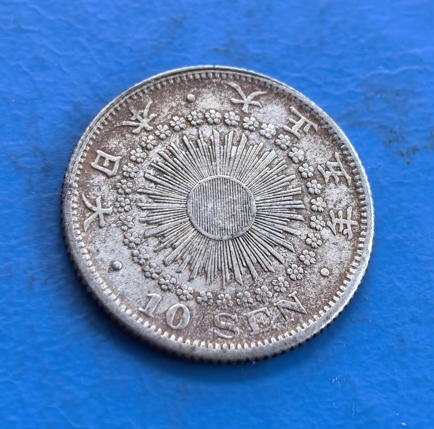 外国优质老铜币高银银币，周六九点倒数截拍，满百包邮，持续收拍 日本大正五年十钱银币，正面 “十钱” 居中，上置菊纹章，桐叶樱花枝环绕，枝叶雕工细腻，蝴蝶结纹饰精巧；背面旭日光芒璀璨，小花点缀，纹饰对称规整，银质温润，尽显日式钱币美学。