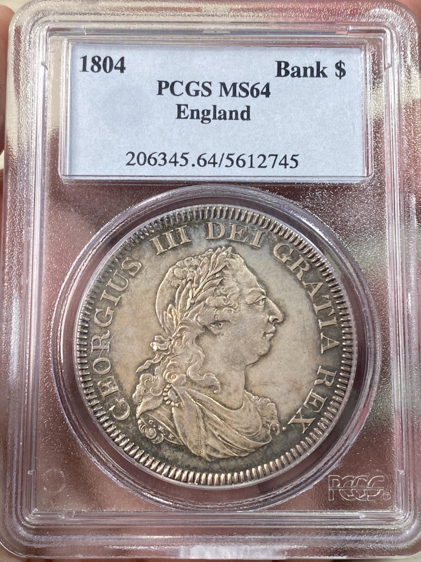 万国钱币拍卖第060期（万国六十期纪念大拍） PCGS MS64 1804英国乔治三世英格兰银行5先令大银 英国白银短缺时期的产物 直接压印在西班牙双柱之上 流通非常充分从而高品难得一见 双面均匀一色的香槟金彩极美 不可多得的典藏级品质 PC老白盒品质保证 高分越来越贵的品种 HA最近2枚64成交价均超过4000美金（盒子有裂）