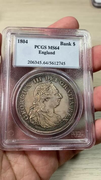 万国钱币拍卖第060期（万国六十期纪念大拍） PCGS MS64 1804英国乔治三世英格兰银行5先令大银 英国白银短缺时期的产物 直接压印在西班牙双柱之上 流通非常充分从而高品难得一见 双面均匀一色的香槟金彩极美 不可多得的典藏级品质 PC老白盒品质保证 高分越来越贵的品种 HA最近2枚64成交价均超过4000美金（盒子有裂）