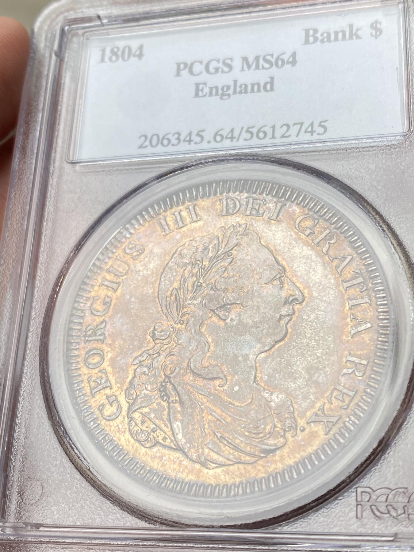 万国钱币拍卖第060期（万国六十期纪念大拍） PCGS MS64 1804英国乔治三世英格兰银行5先令大银 英国白银短缺时期的产物 直接压印在西班牙双柱之上 流通非常充分从而高品难得一见 双面均匀一色的香槟金彩极美 不可多得的典藏级品质 PC老白盒品质保证 高分越来越贵的品种 HA最近2枚64成交价均超过4000美金（盒子有裂）