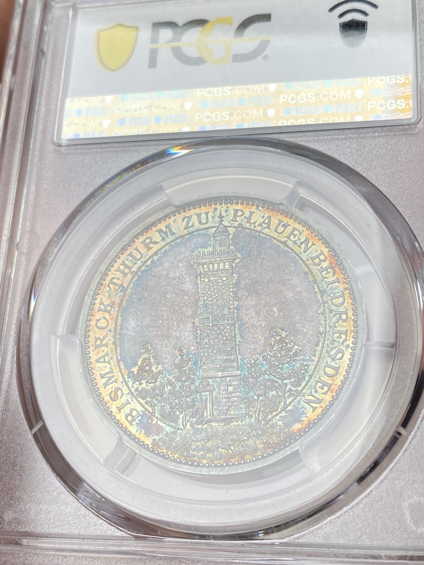 万国钱币拍卖第060期（万国六十期纪念大拍） PCGS SP64 1896年德国德累斯顿-普劳恩俾斯麦纪念塔建成纪念银章 唯一评级记录 冠军分顶级状态。极稀品种。精制工艺，浮雕镜面紫罗兰五彩，实物绝美。正面：普劳恩市华丽纹章。背面：森林中的俾斯麦纪念塔，雕刻细节极佳。俾斯麦纪念塔旨在充当火炬灯塔，塔上的火盆会在特定的日子点燃，以纪念这位铁血宰相在1871年统一德国的功绩。