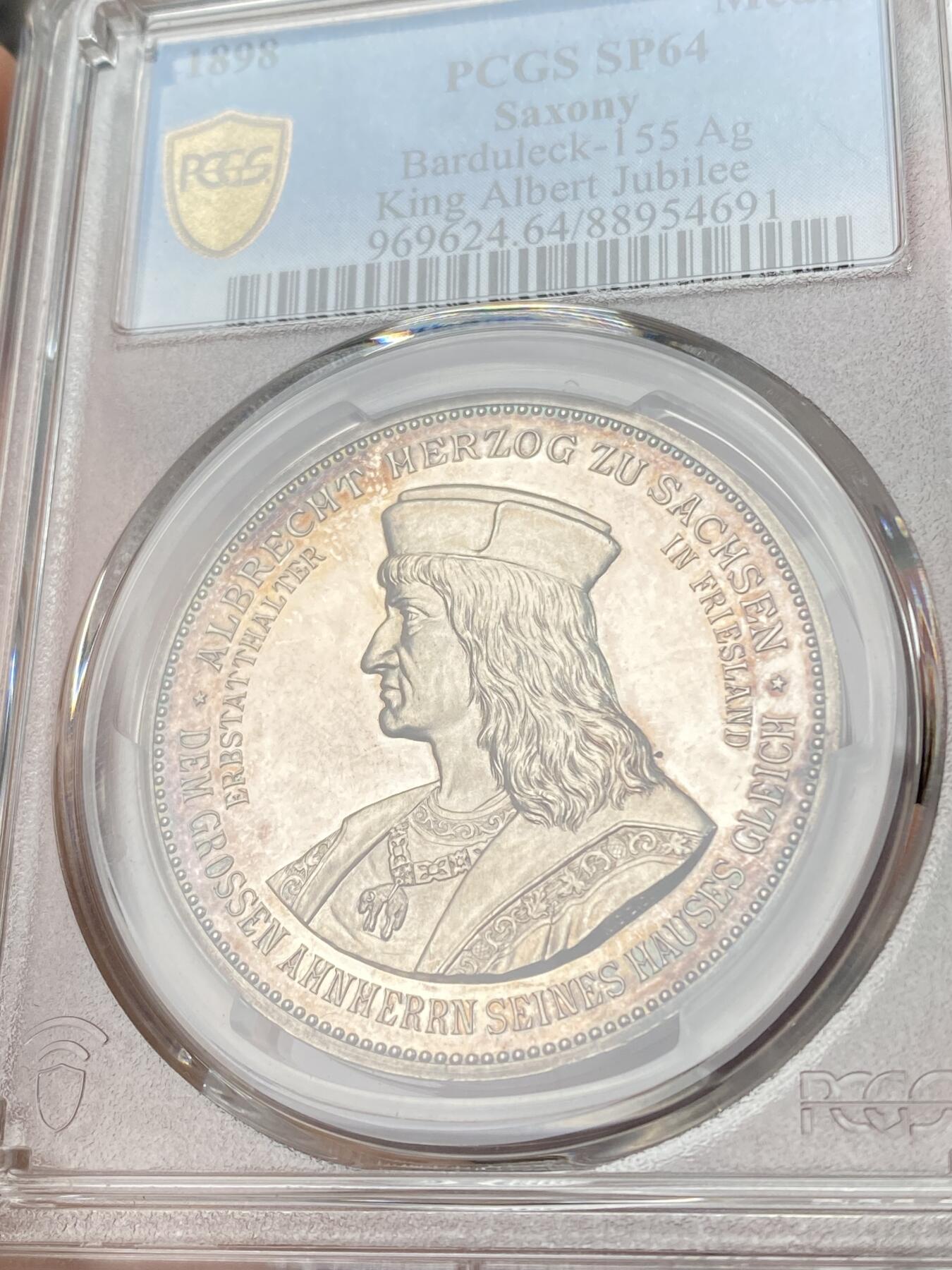 万国钱币拍卖第060期（万国六十期纪念大拍） PCGS SP64 1898年德国萨克森国王阿尔伯特金禧纪念银章 御极二十五周年 唯一记录冠军分 强镜面喷砂精铸，PP模具高浮雕，人物雕刻极其精细，栩栩如生。光边。少见品种。正面:萨克森公爵阿尔伯特半身像，头戴红色公爵圆帽，胸口挂着金羊毛勋章。他创立了韦廷家族的阿尔伯特支系。背面:萨克森国王阿尔伯特戎装半身像，身着大元帅服，头戴普鲁士元帅尖顶盔，佩戴大铁十字勋章。精工细作，实物极其漂亮。