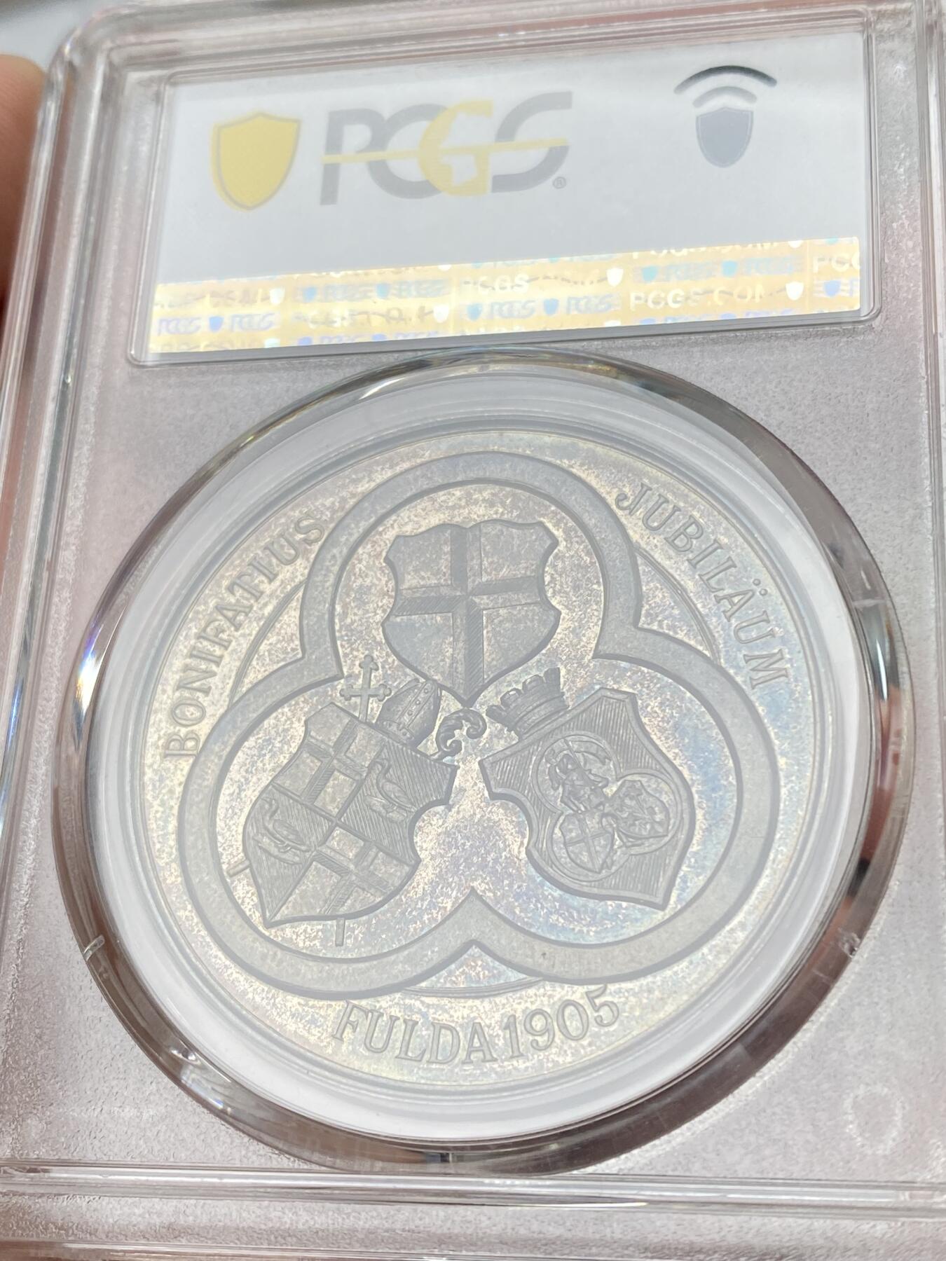 万国钱币拍卖第060期（万国六十期纪念大拍） PCGS MS65 1905年德国黑森富尔达圣博尼法斯逝世1150年纪念银章 稀有品种 唯一评级记录冠军分 浮雕精铸，百年纸袋彩浆。正面:圣博尼法斯全身像，右手举着十字架，左手拿着传道权杖，日耳曼尼亚的守护神。朱庇特万神之王圣橡树被砍倒后发出了新芽。背面:三叶草圈环内的三面盾徽。朱庇特万神之王橡树是日耳曼教徒的一棵圣树。圣树受到日耳曼各民族的广泛崇敬，其木材被用来在圣彼得教堂的原址建造教堂。