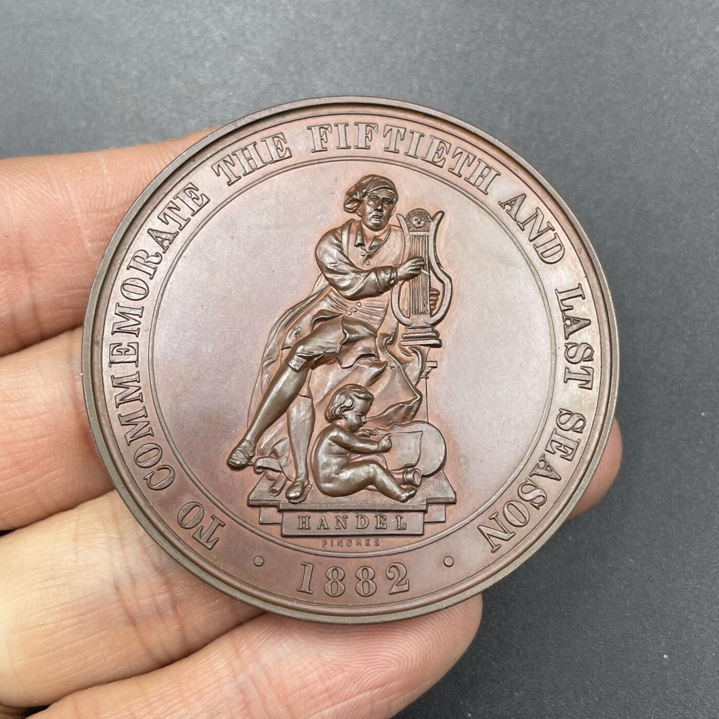 「木头集藏」章牌专场-第67场 1882年英国圣乐协会铜章，直径：51 mm， 62 g，圣乐协会成立于1832年，以推广亨德尔的宗教音乐而闻名，尤其每年举办的《弥赛亚》演出是伦敦的文化盛事。1882年，协会举办了第50届也是最后一届演出季，这枚章牌正是为了纪念这一落幕时刻而铸造，完整见证了19世纪英国古典音乐的一段重要历程。