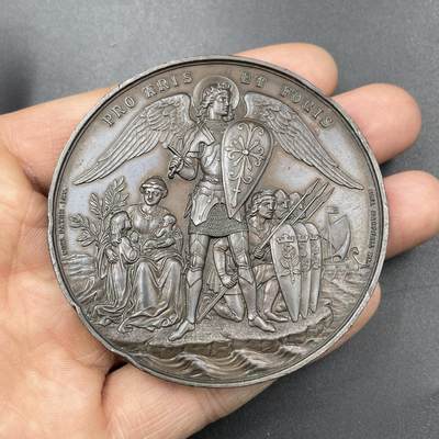 「木头集藏」章牌专场-第67场 - 1881年英国志愿兵运动21周年纪念铜章，直径：63.5mm，93.8 g，中央刻画天使长米迦勒（St. Michael），他身披盔甲、手持盾牌与宝剑，象征着守护与勇气。左侧是怀抱孩子的母亲与少女，手持橄榄枝，代表家园与和平；右侧是跪姿的志愿兵与列队士兵，背景还有帆船，呼应了志愿兵海陆防御的职责。