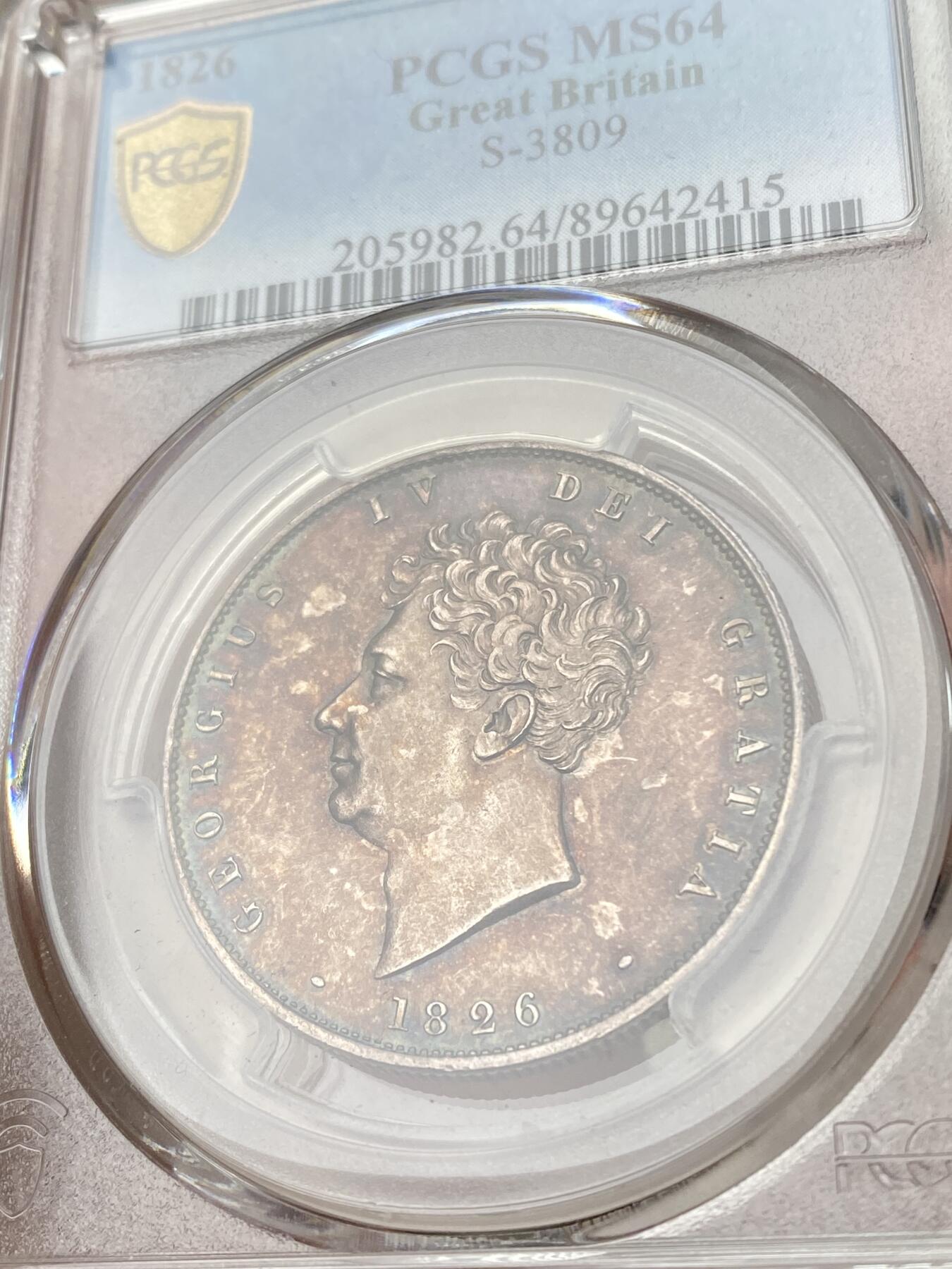 万国钱币拍卖第060期（万国六十期纪念大拍） PCGS MS64 1826年英国乔治四世国王1/2克朗银币 ESC显示1826比1825要略少一些，正反双面留下在纸袋中孕育而出的英伦五彩，赭褐色包浆在边缘流转成了紫罗兰与靛青。乔治四世以其出众的艺术品味闻名于英国上流社会，他钦点用于币面的头像有着非同一般的艺术造诣。
