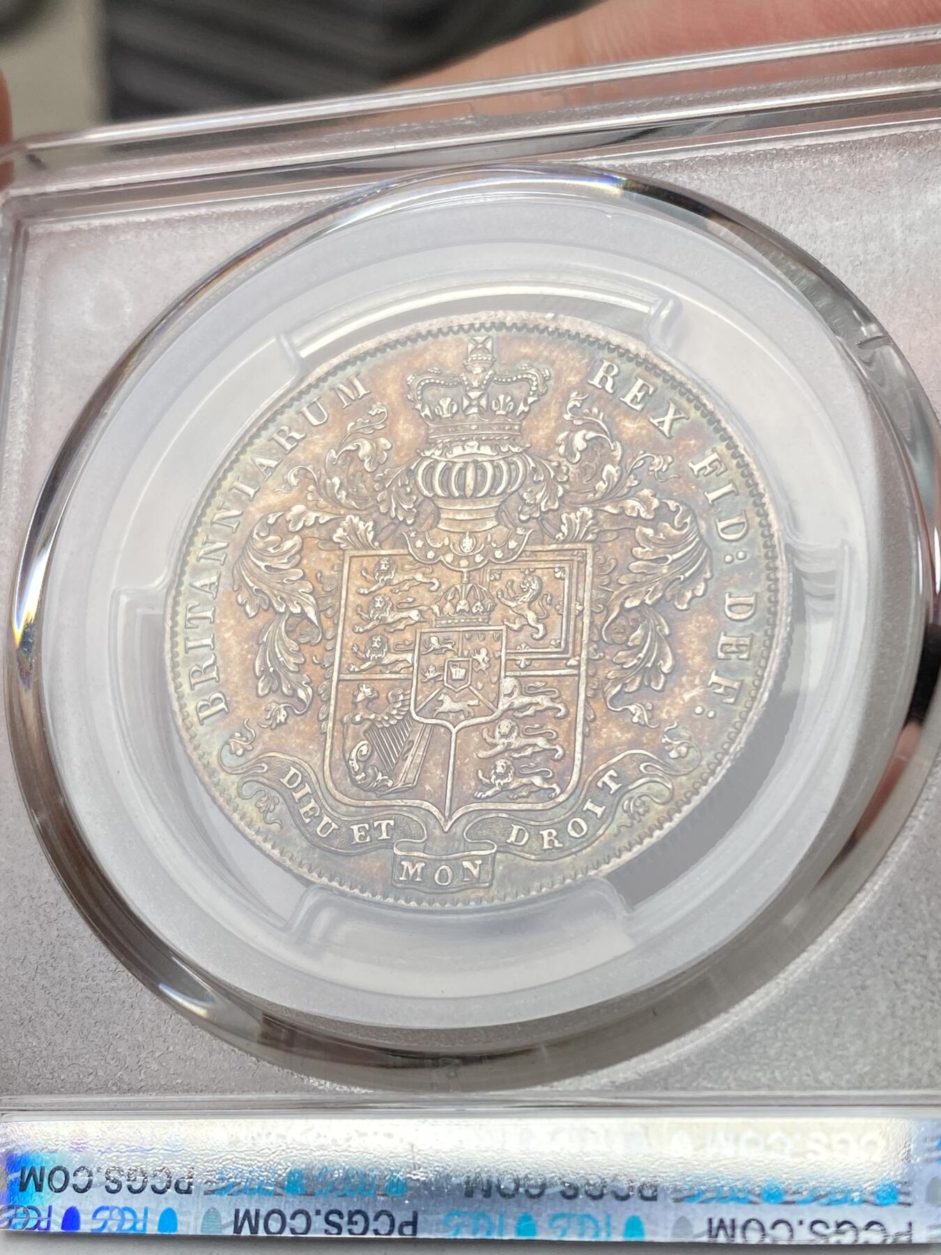 万国钱币拍卖第060期（万国六十期纪念大拍） PCGS MS64 1826年英国乔治四世国王1/2克朗银币 ESC显示1826比1825要略少一些，正反双面留下在纸袋中孕育而出的英伦五彩，赭褐色包浆在边缘流转成了紫罗兰与靛青。乔治四世以其出众的艺术品味闻名于英国上流社会，他钦点用于币面的头像有着非同一般的艺术造诣。
