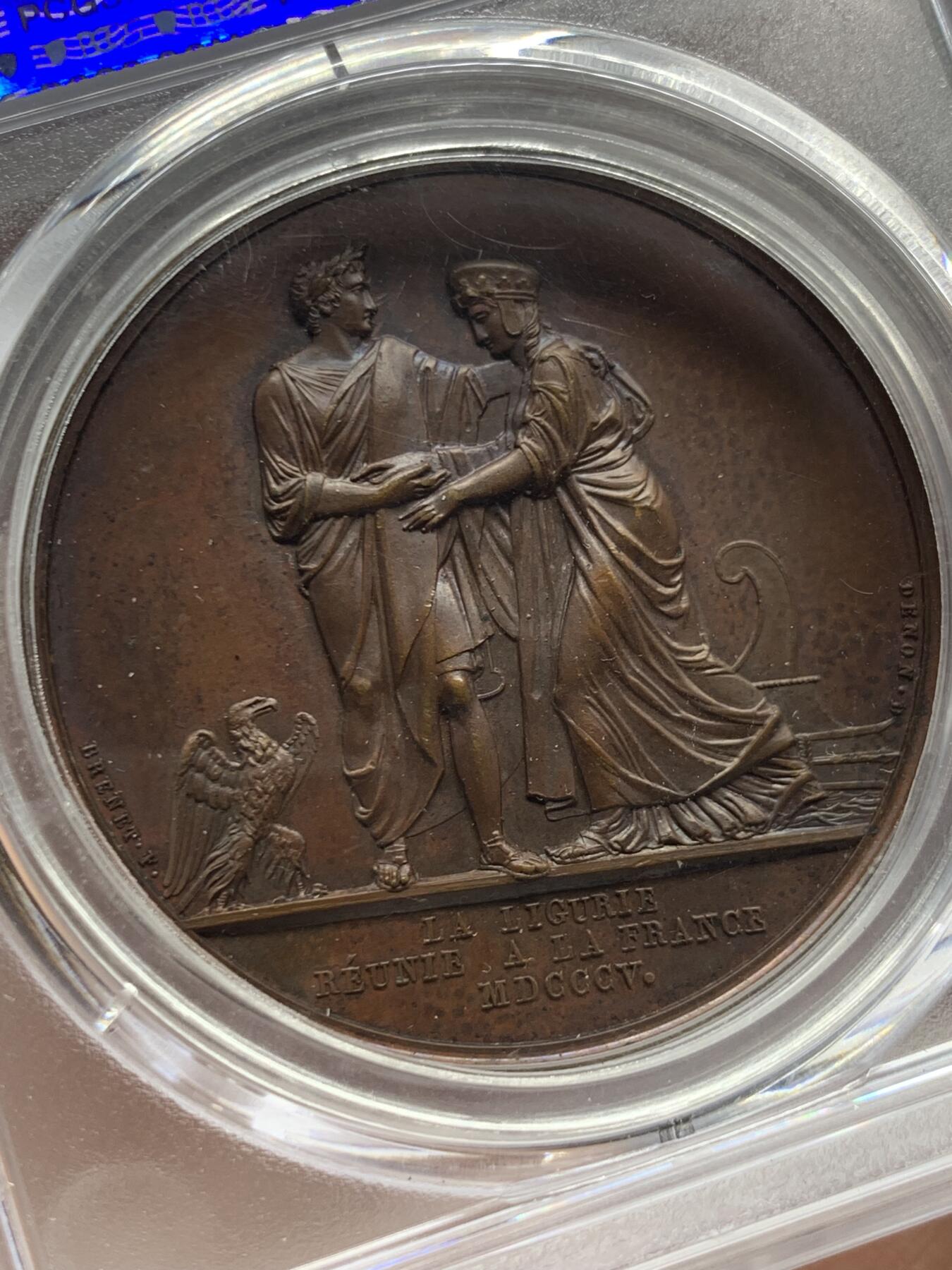 《竞宝斋》第463-465场 周日，周一，周二，3场连拍 （全场包邮）欢迎送拍 PCGS SP64 亚军分 法国1805年拿破仑一世吞并利古里亚原铸铜章 巴黎造币厂 巧克力包浆 左边拿破仑身穿古罗马元老院服饰cos凯撒，接受右边着罗马将军长袍的利古里亚首领低头屈服，两侧饰有象征性的鹰和船头，记录着拿皇攻城略地的丰功伟绩，衣服缕缕毕现生动刻画，人像稀少品种，加厚盒，标签可晃动。仅一枚更高分