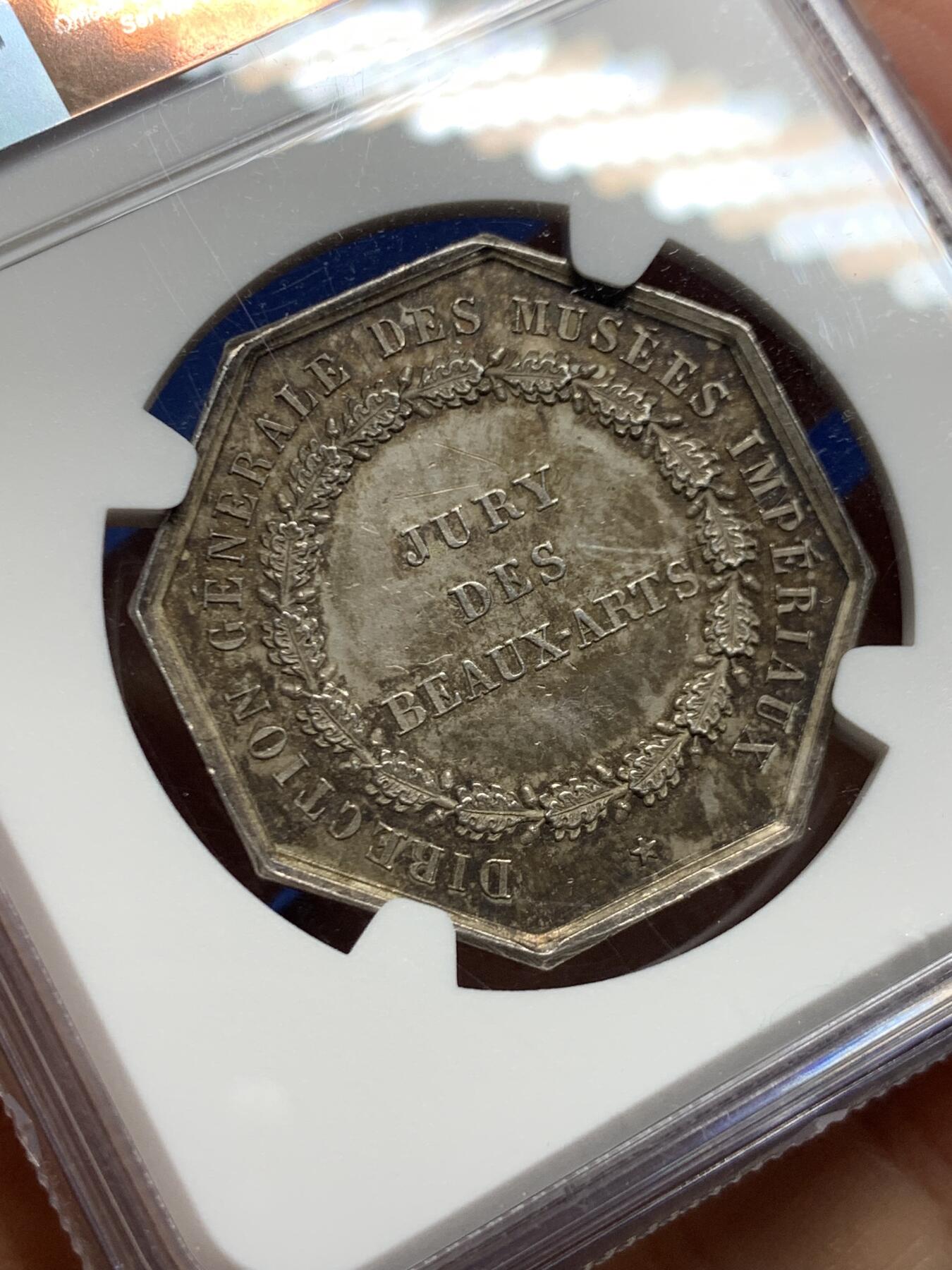 《竞宝斋》第463-465场 周日，周一，周二，3场连拍 （全场包邮）欢迎送拍 NGC MS63 帝国博物馆艺术评审团（Art Jury of Imperial Museum）银质八角代币，正面中央为帝国鹰徽，鹰立于盾徽之上，盾徽外覆披风并加冕皇冠，周围辅以勋章、绶带与权杖元素，构成完整的帝国象征体。