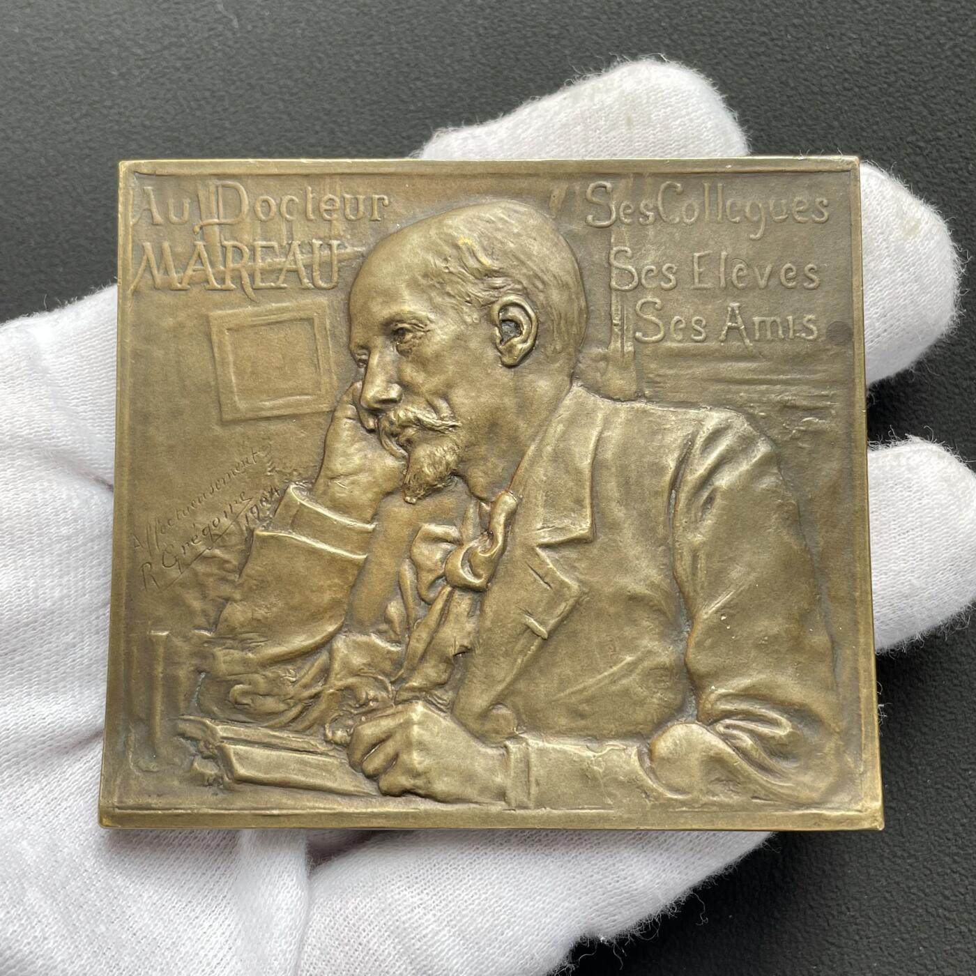 「木头集藏」“ 新岁撷珍”——章牌精品专场！ Rene Gregoire～1904年法国马罗医生铜方章 ，尺寸：70 × 62mm，148 g，罕见品种！马耶尔目录（1870-1940年法国章牌艺术）245号作品。古斯塔夫·马罗（1850-1918年）是昂热医学院的教授，昂热市有一条街道以他的名字命名。正面是正在沉思的马罗医生，背面科学女神与艺术女神徜徉在繁花似锦的卢瓦尔河河畔。