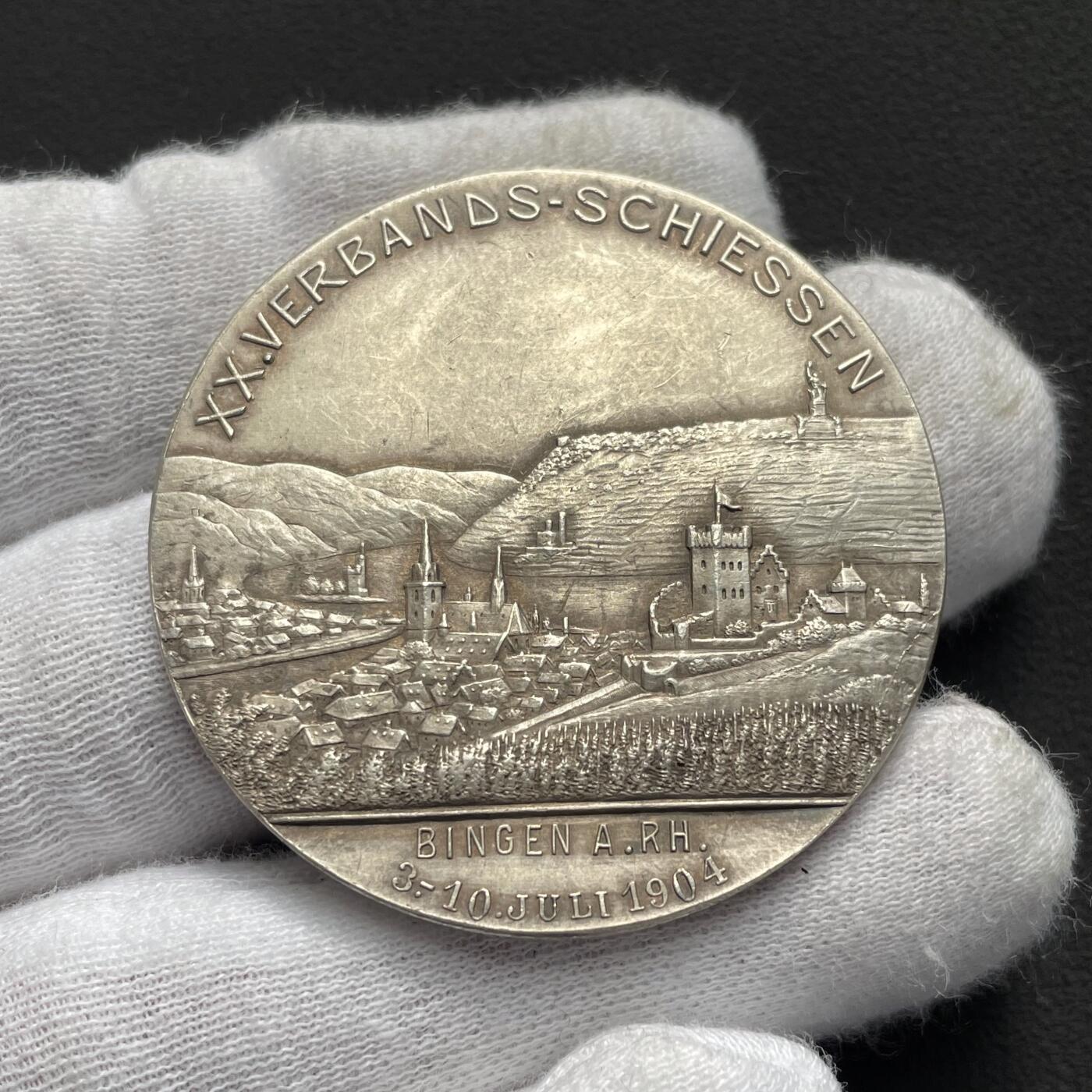 「木头集藏」“ 新岁撷珍”——章牌精品专场！ Balmberger～1904年德国宾根第20届协会射击节银章 ，直径：43 mm，35.5 g，少见品种，正面是黑森大公国恩斯特·路德维希大公的戎装像，背面是莱茵河畔的宾根城市景观，其中著名地标建筑包括河中小岛上的鼠塔，近处的圣马丁大教堂和克洛普城堡，以及远处山顶的尼德瓦尔德纪念碑。这座纪念碑是为纪念德国统一而建，基座上矗立着德意志国家的化身日耳曼尼亚女神。。