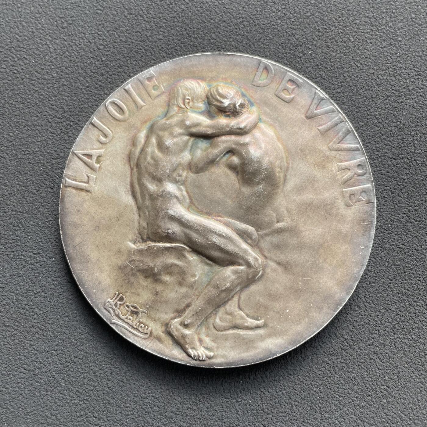 「木头集藏」“ 新岁撷珍”——章牌精品专场！ R. Lamourdedieu～1906年法国SAMF协会35号作品银章“生活的乐趣” ，法兰西章牌之友协会（SAMF）1906年发行，直径：57mm，83 g，包浆很漂亮，银章发行量仅70枚，边铭：丰饶角+ARGENT+火蝾螈+限量编号22。正面是一对情侣在热吻，背面是一名男子眺望朝阳。经典清凉章，完美展现人体的力与美。  SAMF协会章是法国新艺术章牌最杰出的代表，历来受到章牌收藏者的追捧。
