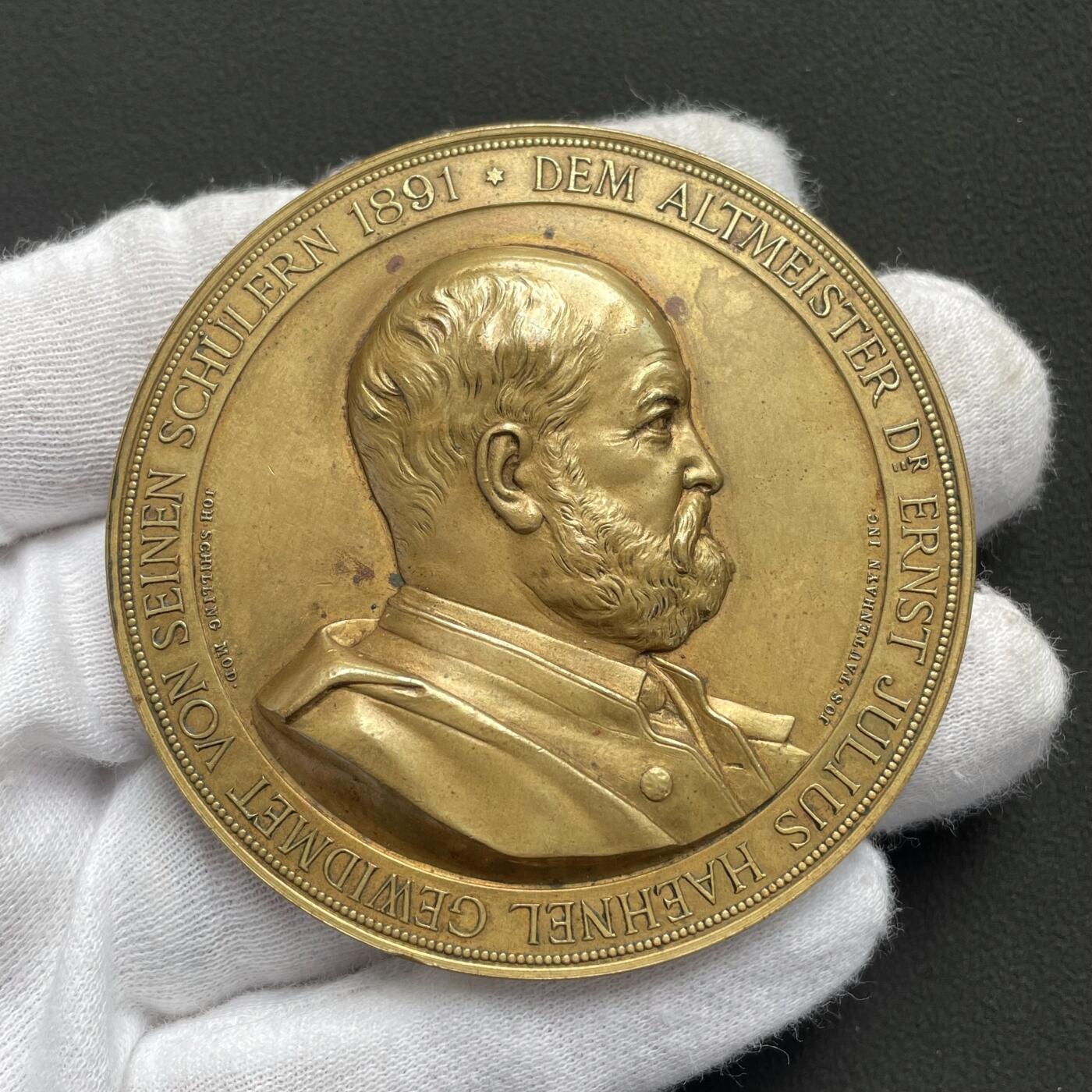 「木头集藏」“ 新岁撷珍”——章牌精品专场！   J. Tautenhayn～1891年德国 雕塑家黑内尔逝世纪念镀金铜章，直径：63 mm，112 g，罕见品种！由德国雕塑家席林和奥地利章牌大师陶滕海因联袂制作。正面是黑内尔肖像，背面半裸女神拨动琴弦，身下狮身人面的形象非常惊艳，兼具成熟女性的魅力与野兽的矫健。  恩斯特·尤利乌斯·黑内尔（1811-1891年）是19世纪德国最负盛名的雕塑家之一。