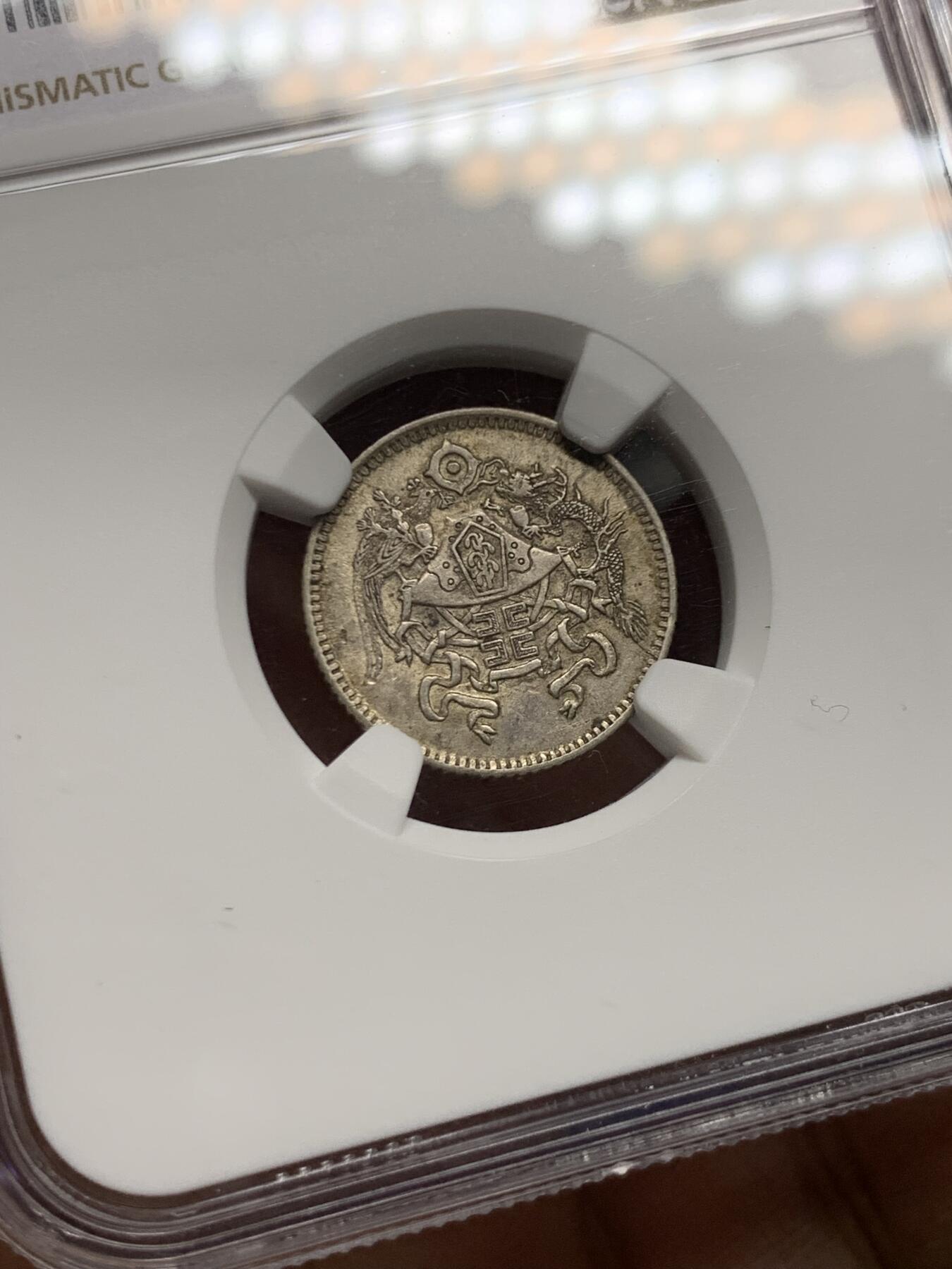 《竞宝斋》第464场 周日，周一，周二，3场连拍 （全场包邮）欢迎送拍 NGC AU58 龙凤壹角 中华民国十五年十二章龙凤黼黻嘉禾壹角银币 原状态好彩老味道，未下过水，淡金彩很好看。十二章国徽是民国13年至民国28年间北洋政府时期的国徽，图案取材自「日、月、星、辰、山、龙、华虫、宗彝、藻、粉米、黼、黻」十二章纹，由鲁迅、许寿裳、钱稻荪研拟。