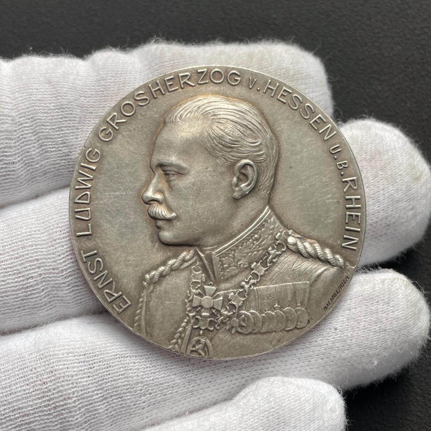 「木头集藏」“ 新岁撷珍”——章牌精品专场！ Balmberger～1904年德国宾根第20届协会射击节银章 ，直径：43 mm，35.5 g，少见品种，正面是黑森大公国恩斯特·路德维希大公的戎装像，背面是莱茵河畔的宾根城市景观，其中著名地标建筑包括河中小岛上的鼠塔，近处的圣马丁大教堂和克洛普城堡，以及远处山顶的尼德瓦尔德纪念碑。这座纪念碑是为纪念德国统一而建，基座上矗立着德意志国家的化身日耳曼尼亚女神。。