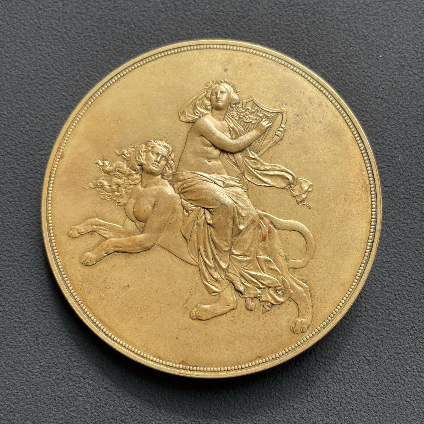 「木头集藏」“ 新岁撷珍”——章牌精品专场！   J. Tautenhayn～1891年德国 雕塑家黑内尔逝世纪念镀金铜章，直径：63 mm，112 g，罕见品种！由德国雕塑家席林和奥地利章牌大师陶滕海因联袂制作。正面是黑内尔肖像，背面半裸女神拨动琴弦，身下狮身人面的形象非常惊艳，兼具成熟女性的魅力与野兽的矫健。  恩斯特·尤利乌斯·黑内尔（1811-1891年）是19世纪德国最负盛名的雕塑家之一。