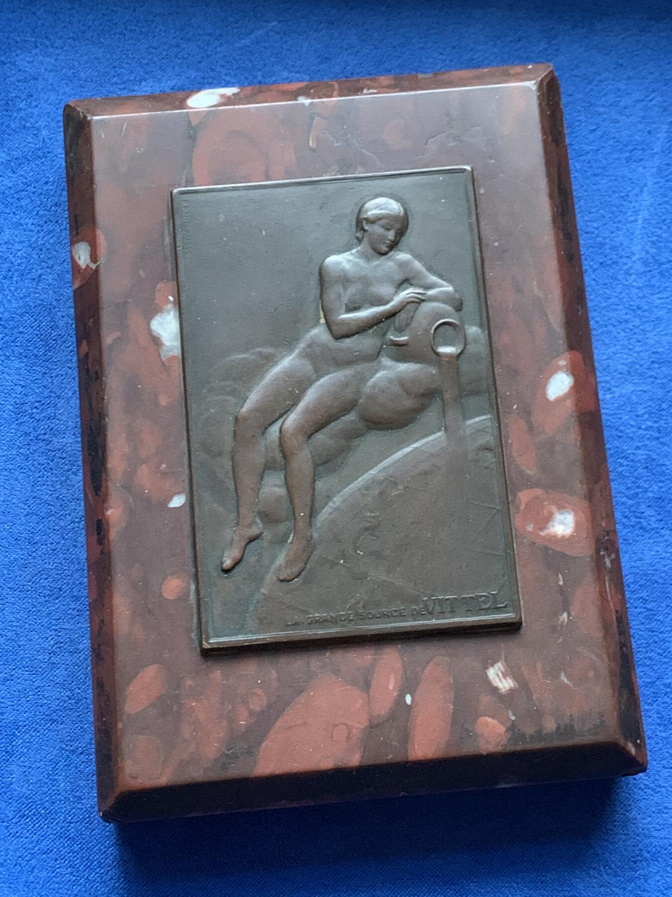 《竞宝斋》第464场 周日，周一，周二，3场连拍 （全场包邮）欢迎送拍 法国维泰勒温泉铜章 (La Grande Sourcede Vittel)嵌石桌面摆件 少见铜章 泉 法国新艺术时期美女清凉章 表现了一位半躺的女性裸体形象，倚靠在象征泉水出口的器形之上，身体姿态柔和，寓意泉水的滋养与生命力。607克，120x85.5x22mm，石板的角略有破损，细节见图。