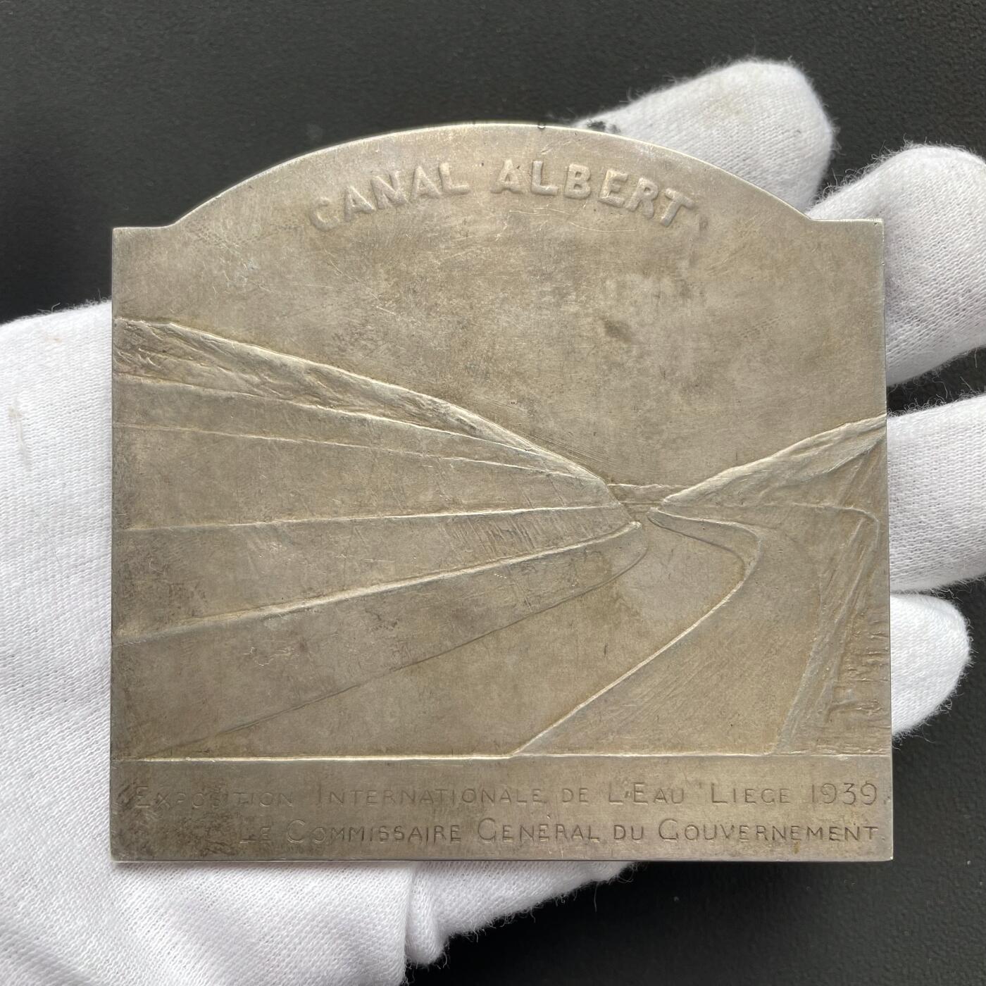 「木头集藏」“ 新岁撷珍”——章牌精品专场！ Devreese～1939年比利时列日水展览会大银章 ， 尺寸：81 × 78 mm ，220 g ，边铭: JF0NS0N A ， 国际水展览会 列日 1939政府总专员  正面: 左侧海神波塞冬手持三叉戟，右侧美人鱼吹响海螺号。 背面: 世界十大运河之一的比利时阿尔伯特运河。 名誉品银章。边缘有一处老的验银锉痕，银章少见，收藏佳品。