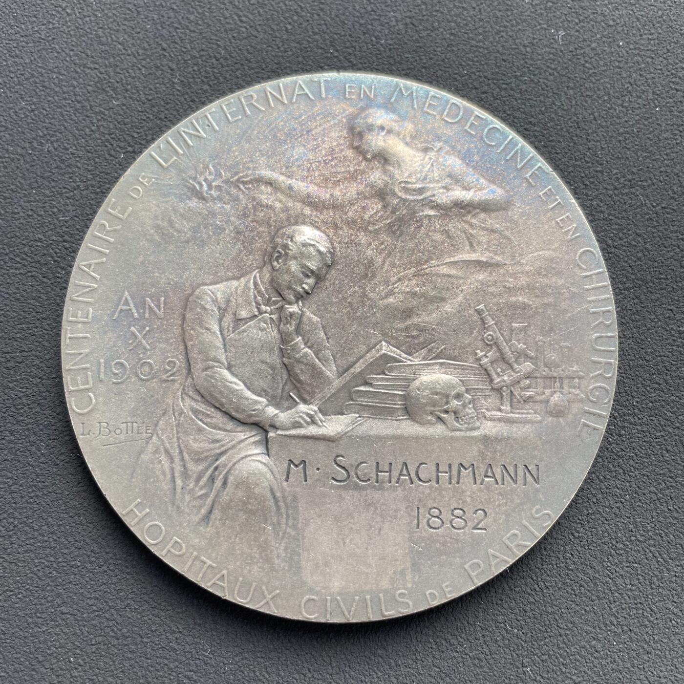 「木头集藏」“ 新岁撷珍”——章牌精品专场！  Louis Bottée～法国巴黎市民医院内科与外科住院医师制度百年纪念镀银大铜章，直径：68 mm，124.5 g，这枚章属于欧洲新艺术风格章牌的经典品种，兼具艺术价值与历史纪念意义。正面：描绘了象征医学的女性形象，俯身关怀病床旁的医生与患者，寓意医学的人文关怀。背景是巴黎圣母院。