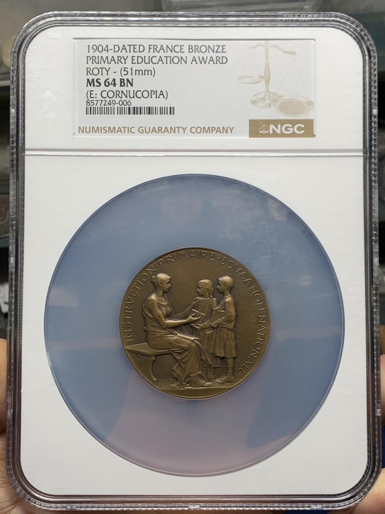 《竞宝斋》第465场 周日，周一，周二，3场连拍 （全场包邮）欢迎送拍 NGC MS64BN 1904年法国初级教育铜章，罗蒂作品，直径51毫米，正面图案展现了一位女性教师向两名学生传授知识的场景，象征着国家对基础教育的重视。加大盒