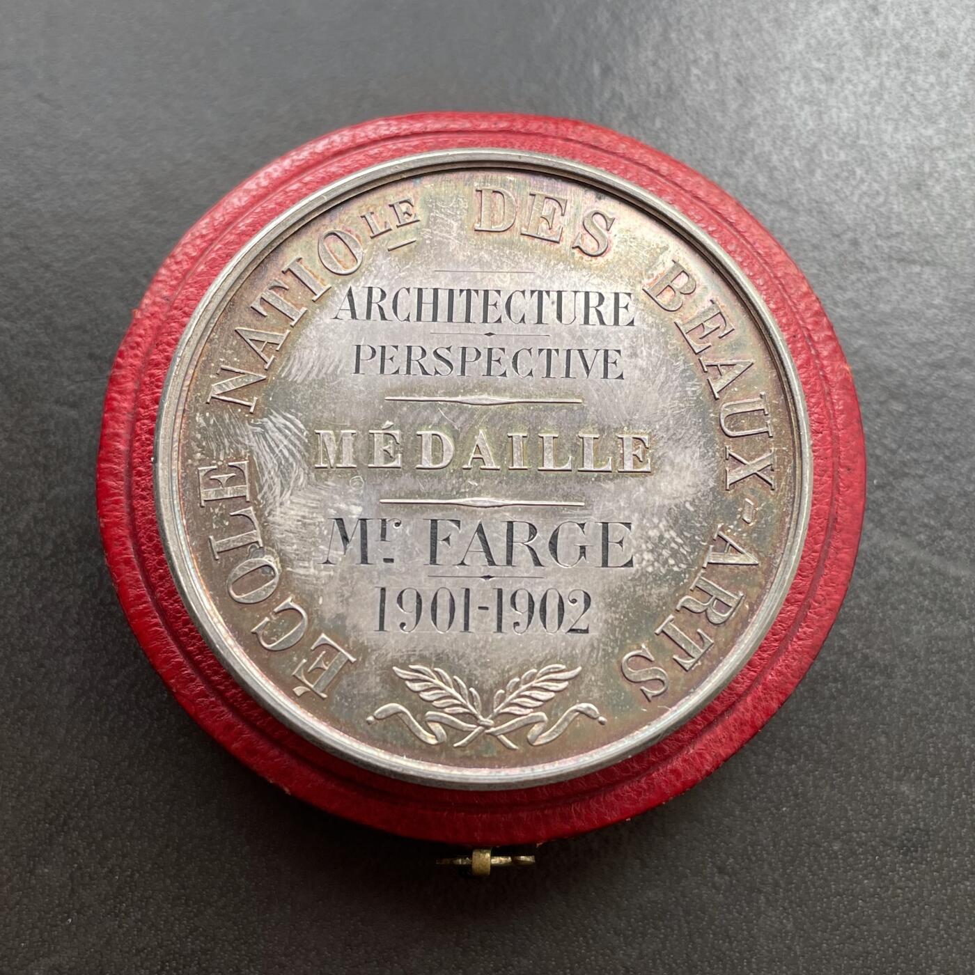 「木头集藏」“ 新岁撷珍”——章牌精品专场！ 1902年法国巴黎国立高等美术学院原盒银章，直径：41 mm，37 g，边铭：丰饶角 ARGENT，三位女性分别代表雕塑（手持锤子与凿子）、建筑（手持标尺与绘图工具）、绘画（手持调色板与画笔）。 左侧小雕像为智慧女神密涅瓦（Minerva），代表艺术创作的理性与灵感。品相不错，彩色氧化很美，原盒正常使用，同款收藏佳品。