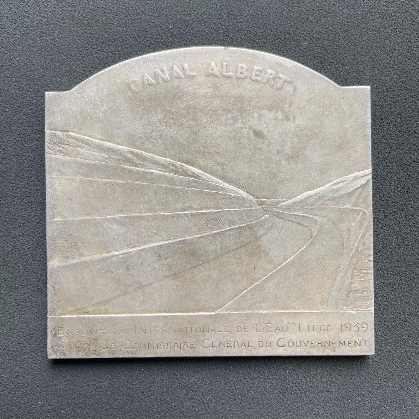 「木头集藏」“ 新岁撷珍”——章牌精品专场！ Devreese～1939年比利时列日水展览会大银章 ， 尺寸：81 × 78 mm ，220 g ，边铭: JF0NS0N A ， 国际水展览会 列日 1939政府总专员  正面: 左侧海神波塞冬手持三叉戟，右侧美人鱼吹响海螺号。 背面: 世界十大运河之一的比利时阿尔伯特运河。 名誉品银章。边缘有一处老的验银锉痕，银章少见，收藏佳品。