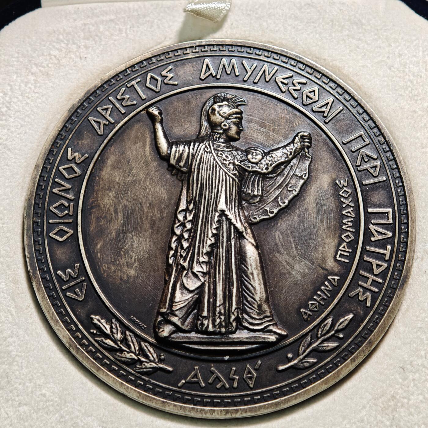 【德藏】世界币章拍卖第164期（拍品征集中~欢迎藏友联系） 20世纪初希腊国防部纪念大银章  直径约：70.3mm；重约：156.1g 欧洲黑包浆，雕刻精美，原装盒子，收藏价值高。正面是头戴战盔、身披长袍的古希腊神话中智慧、战争与守护女神雅典娜的站立像；背面中间是装饰有希腊国徽、海锚、头盔、交叉的箭头等元素的盾牌，盾牌上方文字是希腊语“ΑΜΥΝΕΣΘΑΙ ΠΕΡΙ ΠΑΤΡΗΣ（为祖国而战）”