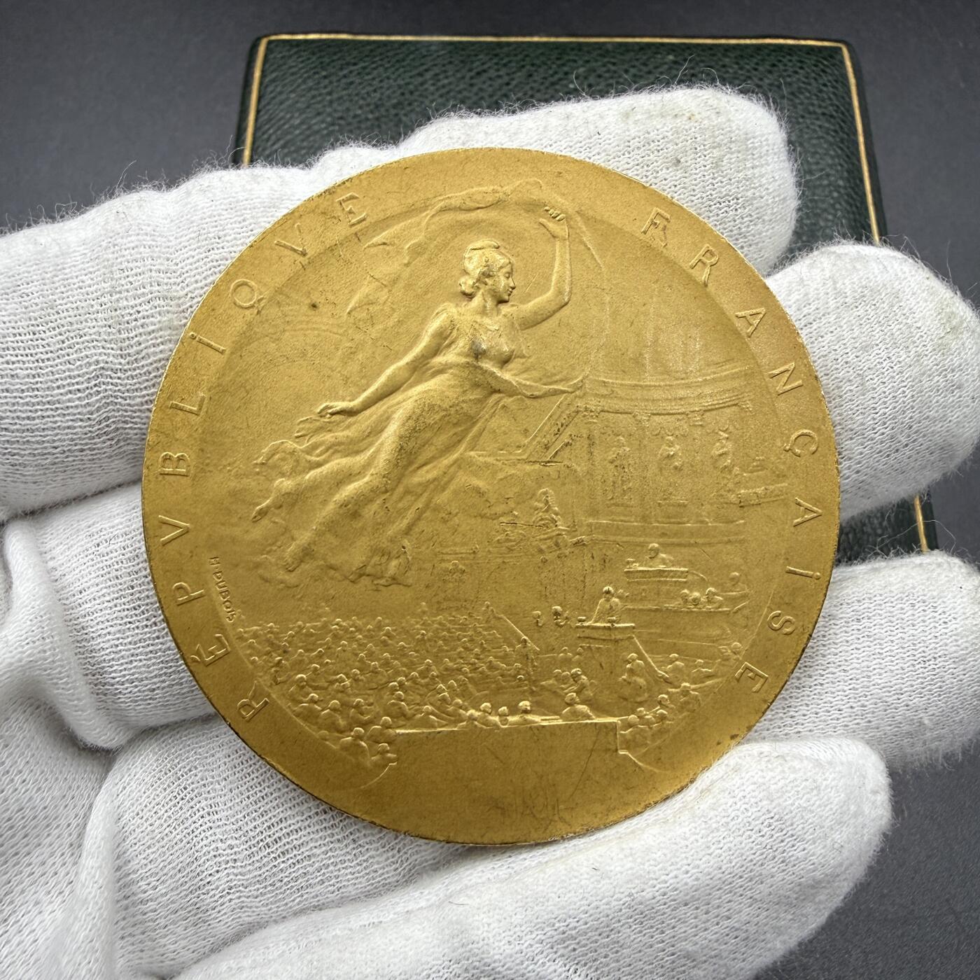 「木头集藏」“ 新岁撷珍”——章牌精品专场！ H. Dubois～1909年法国参议院议员镀金银章，直径：50mm，66 g，边铭：丰饶角 1ARGENT，品相不错，授予1909年担任法国参议院司库的保罗·雅隆（Paul Jallon）。正面刻画象征法兰西共和国的玛丽安娜凌空飞翔在法国参议院议事大厅之上，议员们坐在席位上，前方是演讲台，台下还有密集的旁听人群，还原了当时参议院的议事氛围。背面卢森堡宫 法国参议院所在地，烫金皮盒正常使用！