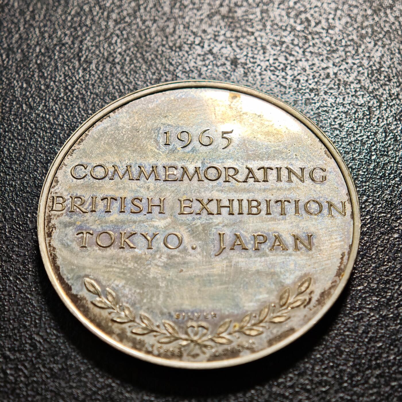 【德藏】世界币章拍卖第164期（拍品征集中~欢迎藏友联系） 1965年 英国纪念日本东京博览会银章 直径约：38.4mm；重约：26.9g 五彩包浆，原盒。正面为一手持三叉戟、一手扶米字盾牌的不列颠尼娅女神坐像，背景有英国议会大厦建筑轮廓；背面是文字“1965 / COMMEMORATING BRITISH EXHIBITION / TOKYO. JAPAN / SILVER（‌1965年英国日本东京博览会纪念银章）”