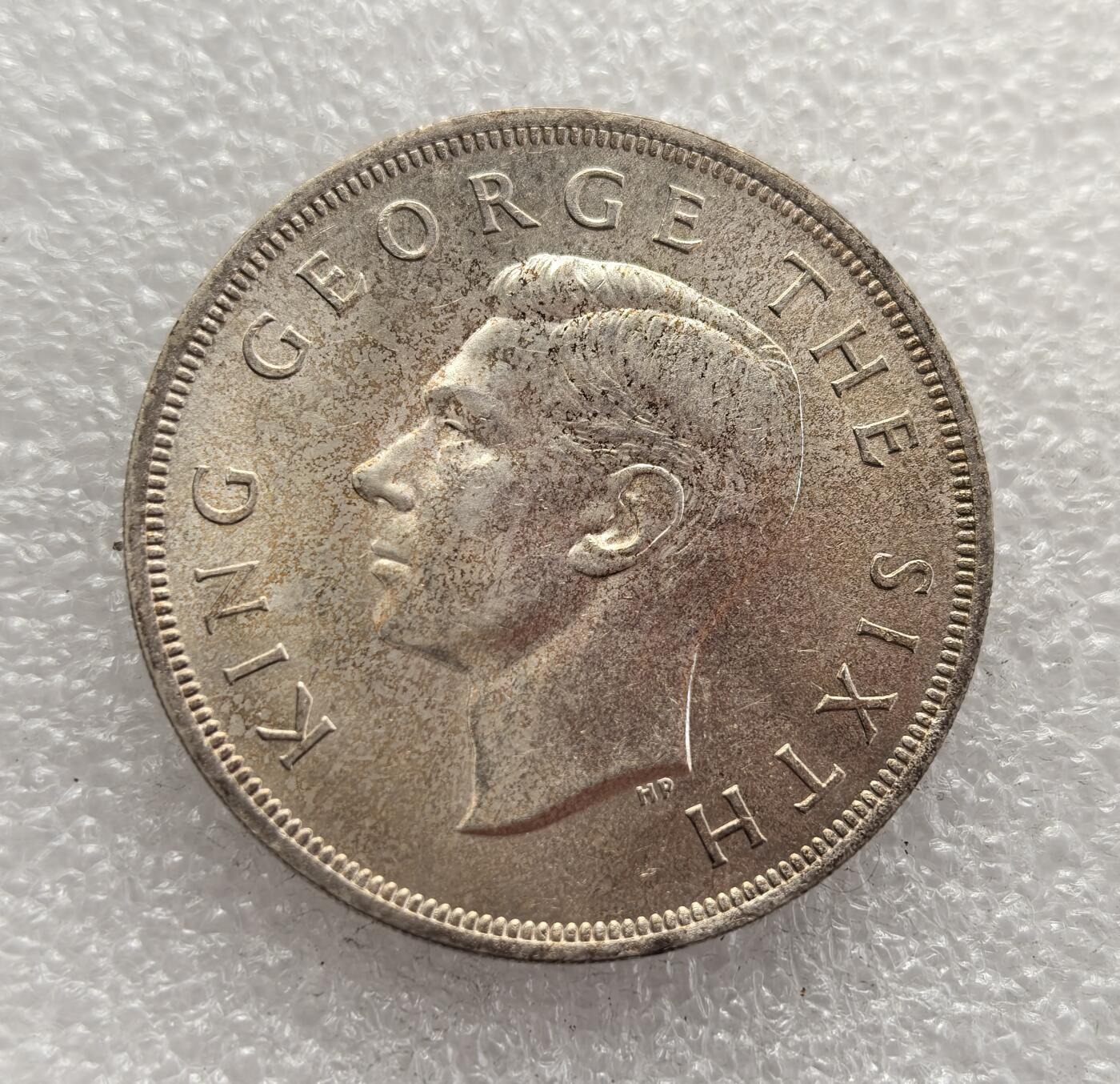 外国优质老铜币高银银币，周六九点倒数截拍，满百包邮，持续收拍，年后发货 新西兰 1949 年1 克朗银币，为纪念英王乔治六世计划出访新西兰而铸造。因国王健康恶化，出访取消，该币成为一场 “未发生的皇家访问” 的纪念物，以银质打造，正面为乔治六世像，背面是新西兰国树银蕨与星纹。