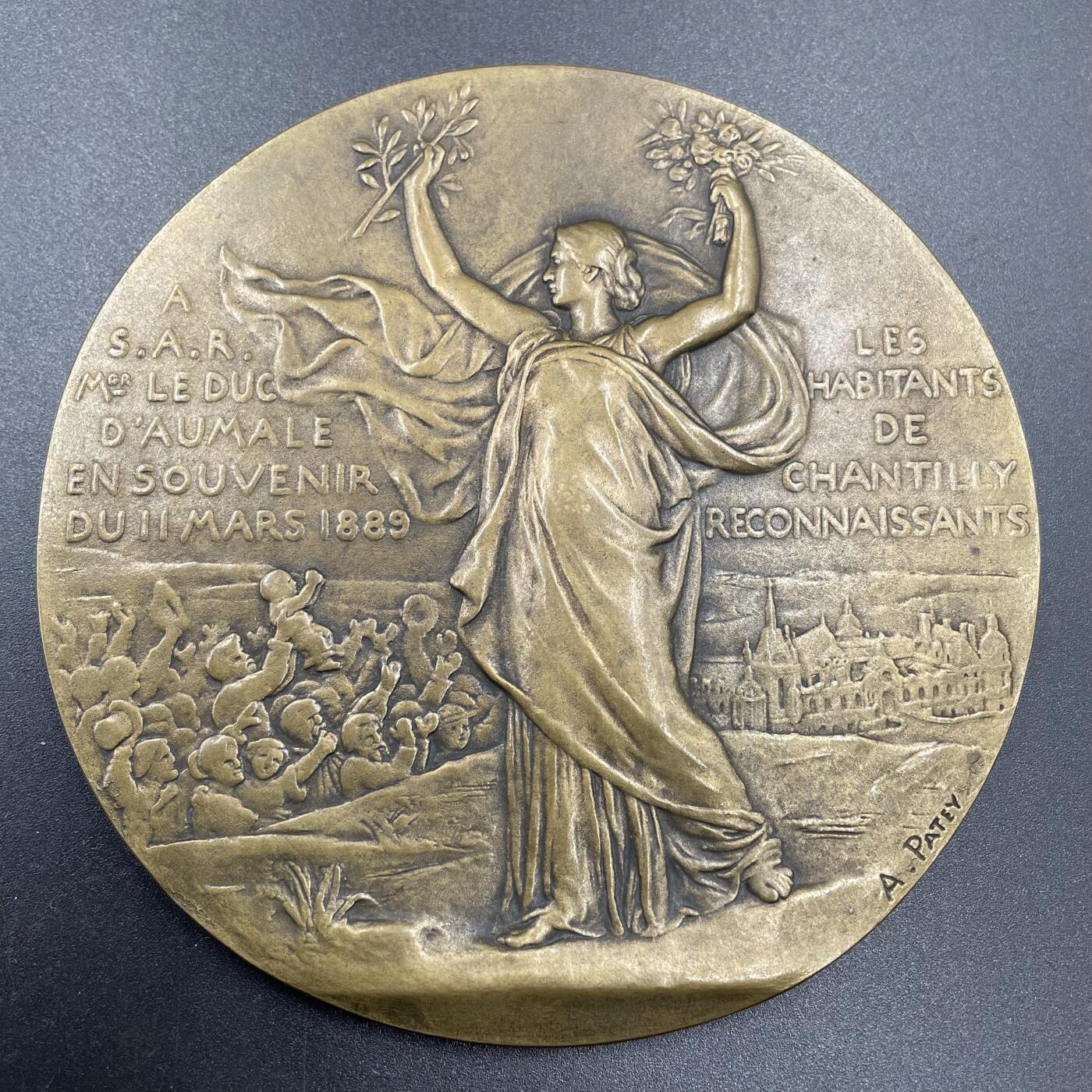 「木头集藏」“ 新岁撷珍”——章牌精品专场！  A.Patey～1889年尚蒂伊市感恩奥马勒公爵大铜章，直径：102 mm，正面身披薄纱的女性，侧身坐在岩石上，手托脸颊望向远方，日出之上刻有FRANCE，象征法国的复兴与希望；背面尚蒂伊市的居民向公爵表达敬意。法语：尚蒂伊市感恩的居民，1889年3月11日，赠予奥马勒公爵殿下，背景是尚蒂伊城堡，这是奥马勒公爵的主要居所，也是法国重要的文化遗产，少见大版，品相不错。