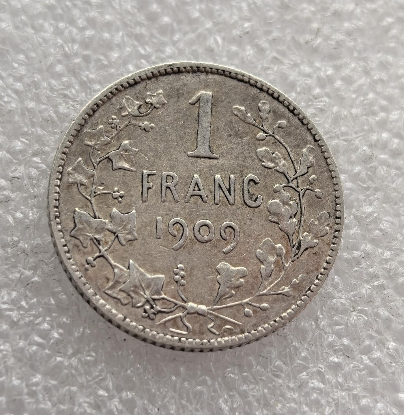 外国优质老铜币高银银币，周六九点倒数截拍，满百包邮，持续收拍，年后发货 比利时 1909 年发1 法郎银币，属于利奥波德二世统治后期的流通货币。当时比利时正处于殖民扩张与工业发展阶段，该币以国王头像与植物花环为设计，银币材质反映了当时比利时的经济实力，是其殖民鼎盛时期的货币见证。