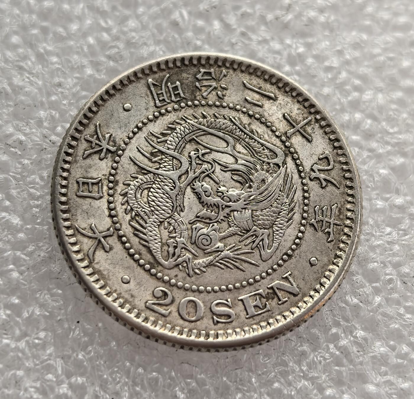 外国优质老铜币高银银币，周六九点倒数截拍，满百包邮，持续收拍，年后发货 日本明治二十九年（1896 年）二十钱银币，是明治维新时期的流通货币。币面的龙纹与菊花纹章，体现了日本近代化转型中 “和魂洋才” 的理念，见证了当时日本工业化扩张与货币体系改革的进程。