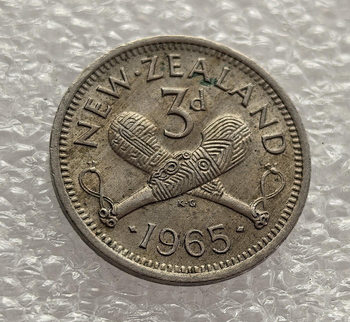 外国优质老铜币高银银币，周六九点倒数截拍，满百包邮，持续收拍，年后发货 新西兰 1965 年3 便士流通硬币，属于伊丽莎白二世时期英联邦货币体系下的旧制货币，是 1967 年新西兰货币十进制改革前的最后一批流通币之一。币面毛利战棍设计融合本土文化与殖民象征，见证了新西兰在英联邦框架下的文化身份构建。
