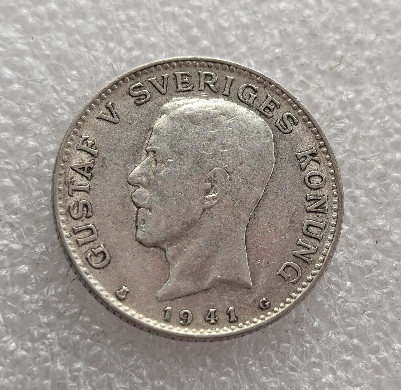 外国优质老铜币高银银币，周六九点倒数截拍，满百包邮，持续收拍，年后发货 瑞典 1941 年1 克朗银币，属于古斯塔夫五世在位时期的流通货币。当时瑞典在二战中保持中立，该币以国王头像与国徽为设计，银币材质也体现了战时瑞典维持货币稳定的努力，是瑞典中立时期经济与政治状态的见证。