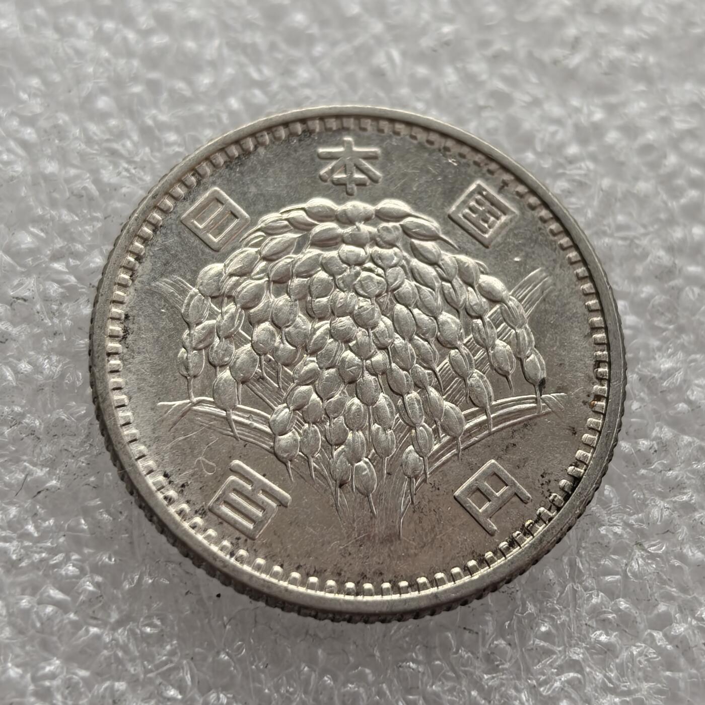 外国优质老铜币高银银币，周六九点倒数截拍，满百包邮，持续收拍，年后发货 日本 1965 年（昭和 40 年）100 日元银币，采用稻穗图案设计，象征日本战后农业的恢复与经济高速增长。它是日本战后货币体系的一部分，反映了当时日本从战后重建走向经济腾飞的社会背景。