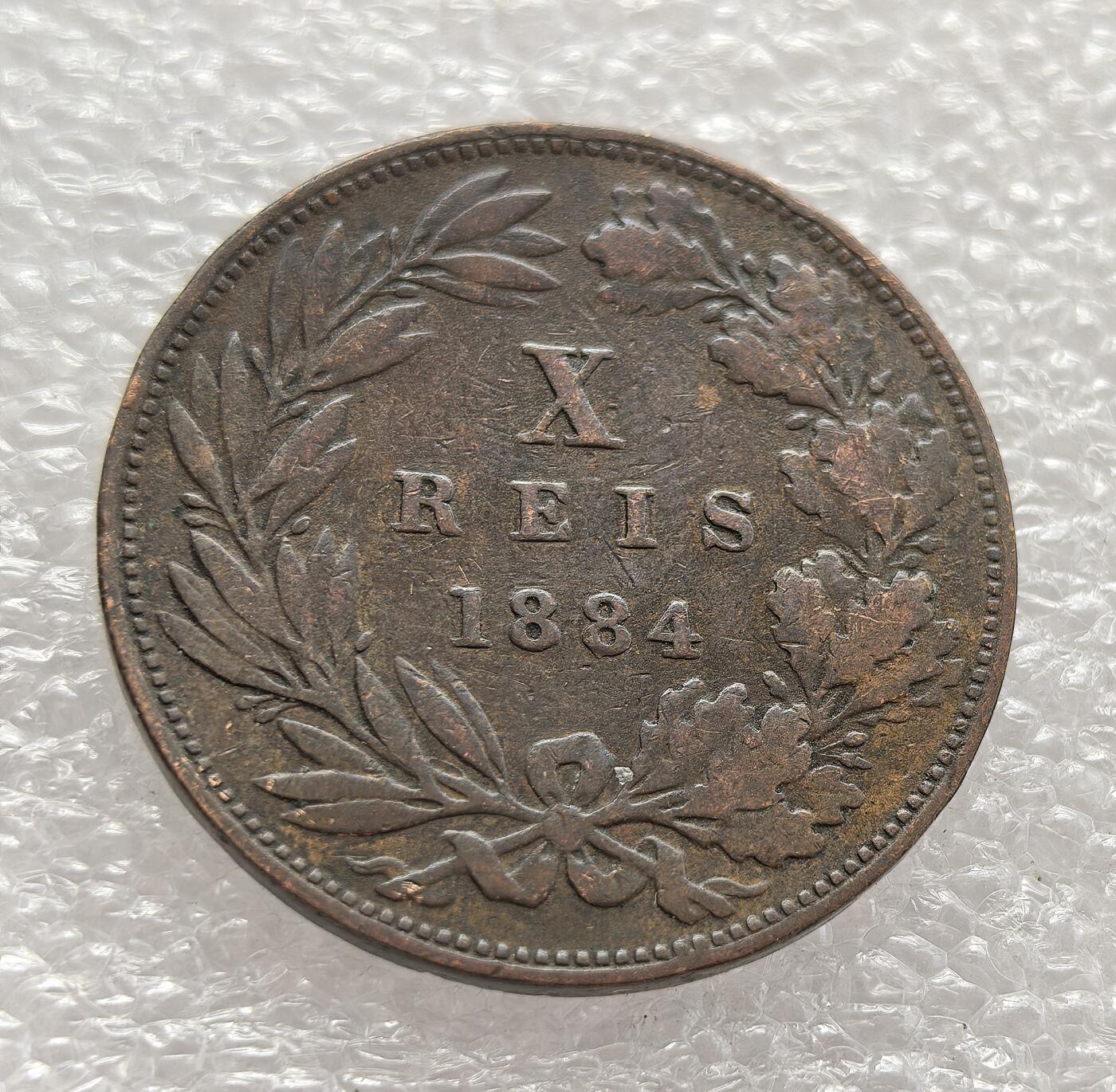 外国优质老铜币高银银币，周六九点倒数截拍，满百包邮，持续收拍，年后发货 葡萄牙王国 1884 年 10 瑞斯铜币，属于路易斯一世统治时期。路易斯一世执政正值葡萄牙殖民扩张鼎盛阶段，非洲殖民活动推动了国内经济与贸易需求，这类小额铜币的发行满足了日常交易需要，也见证了葡萄牙作为殖民帝国的货币体系与经济特征。