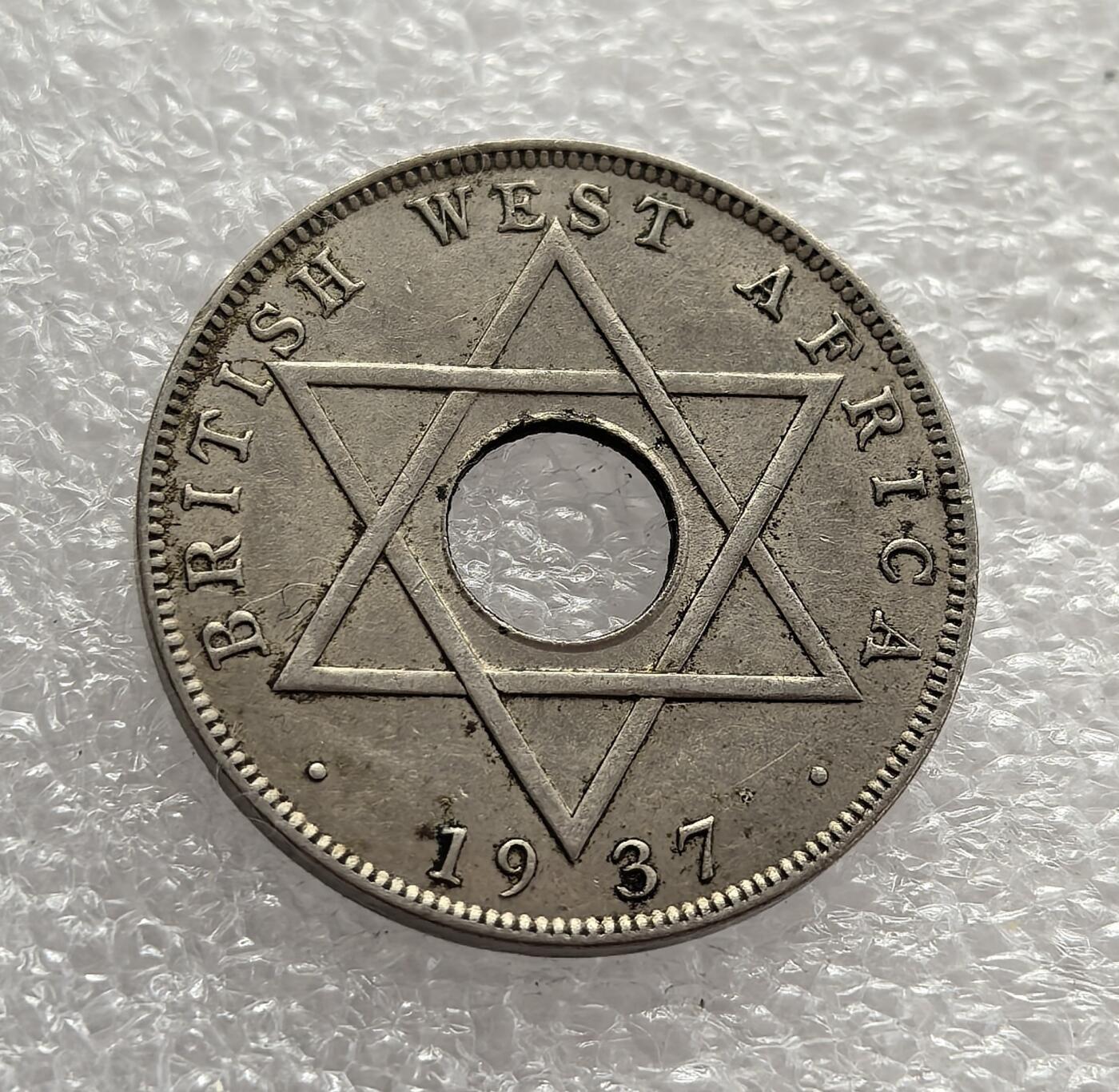 外国优质老铜币高银银币，周六九点倒数截拍，满百包邮，持续收拍，年后发货 英属西非 1937 年半便士流通硬币，正值乔治六世继位初期。币面六芒星是西非殖民货币的标志性图案，中间圆孔是小额硬币的典型设计，阿拉伯文适配西非穆斯林文化，见证了英国殖民统治下的货币统一与文化适配。