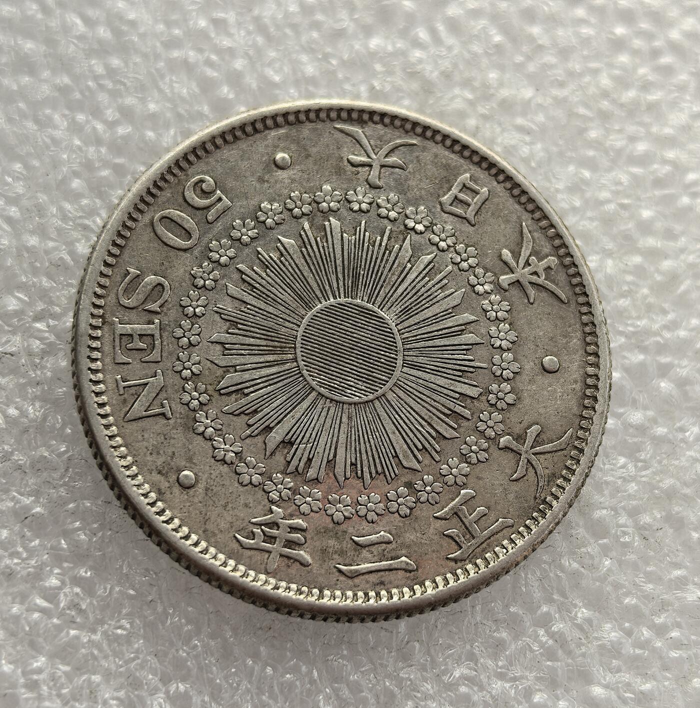 外国优质老铜币高银银币，周六九点倒数截拍，满百包邮，持续收拍，年后发货 日本大正二年（1913 年）五十钱银币，属于大正天皇初期的流通货币。币面的旭日纹与菊花纹章，既延续了明治时期的近代化象征，也反映了大正时代日本在一战前夕的经济扩张与社会转型，是当时货币体系的重要见证。